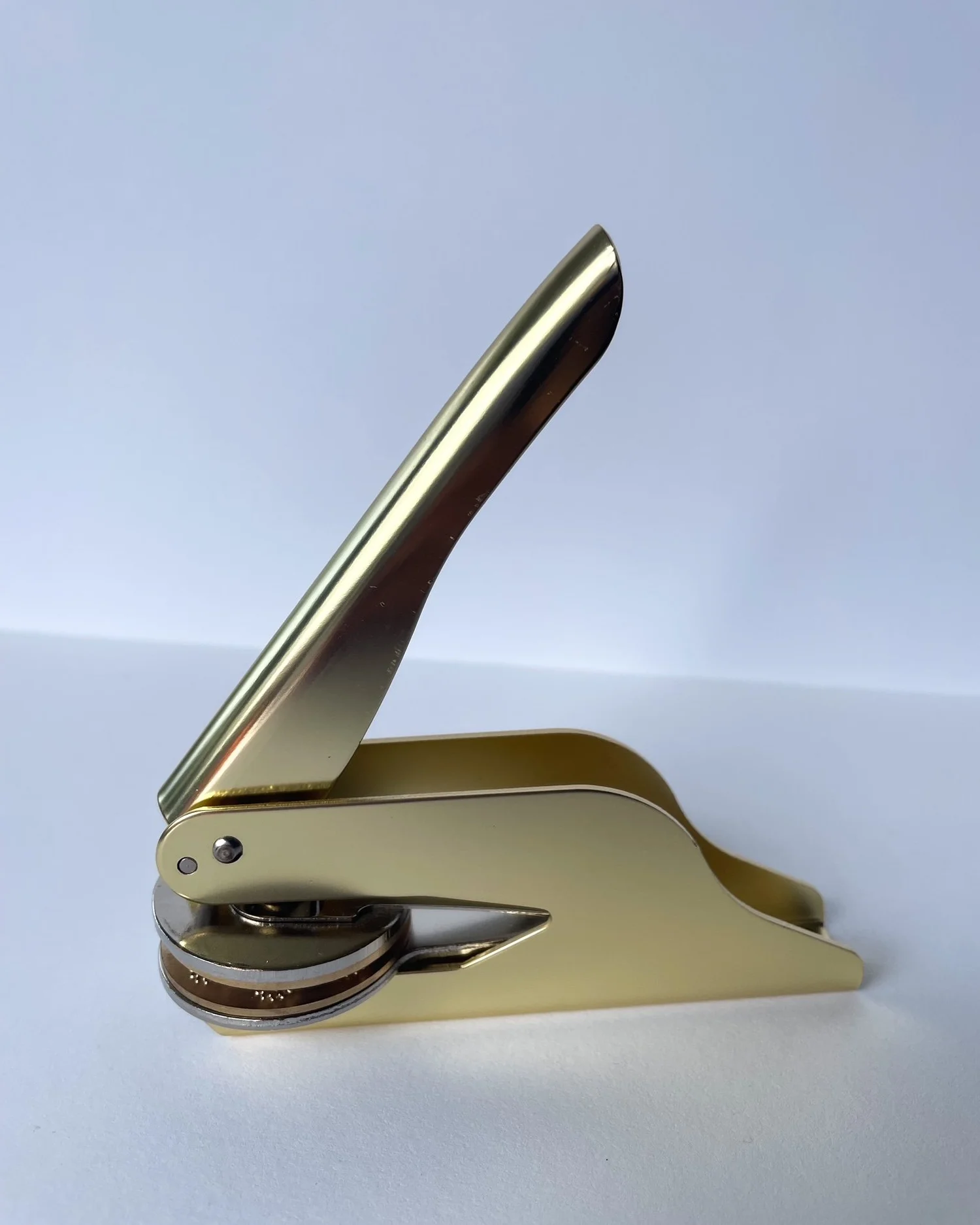 Gold embosser side on to camera. Plain white background.