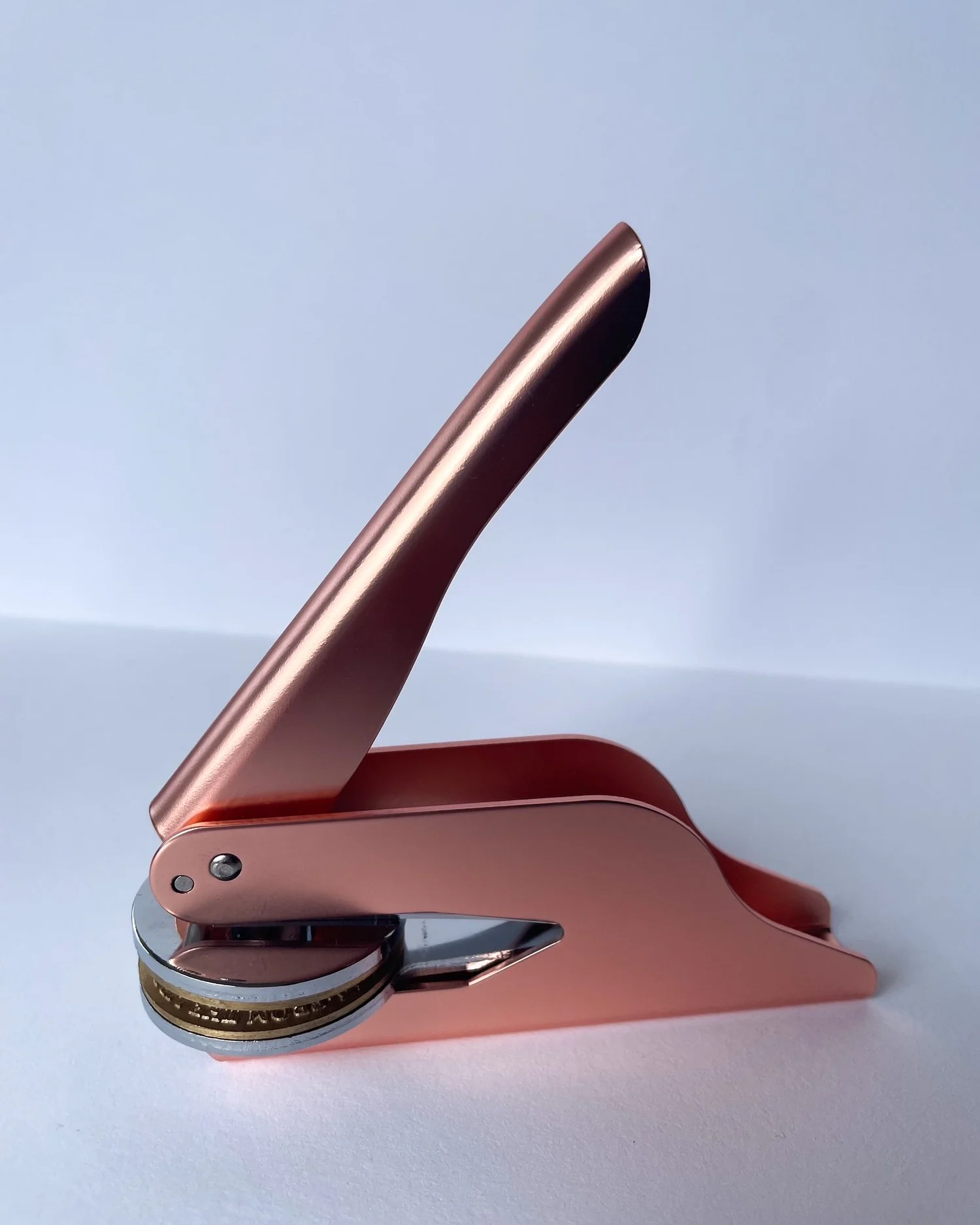 Rose gold embosser side on to camera. Plain white background.