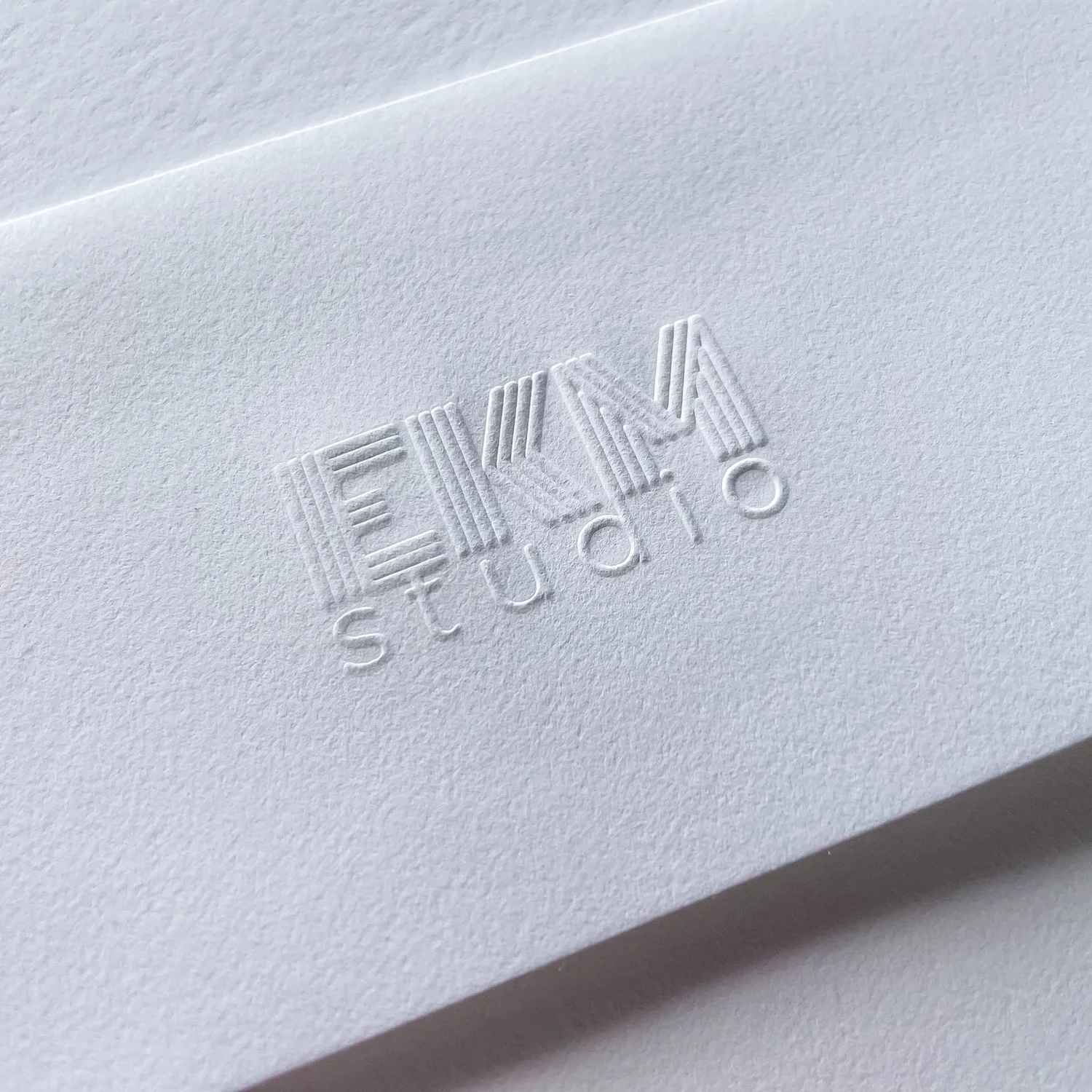 Square-flap envelope with EKM Studio logo embossed.
