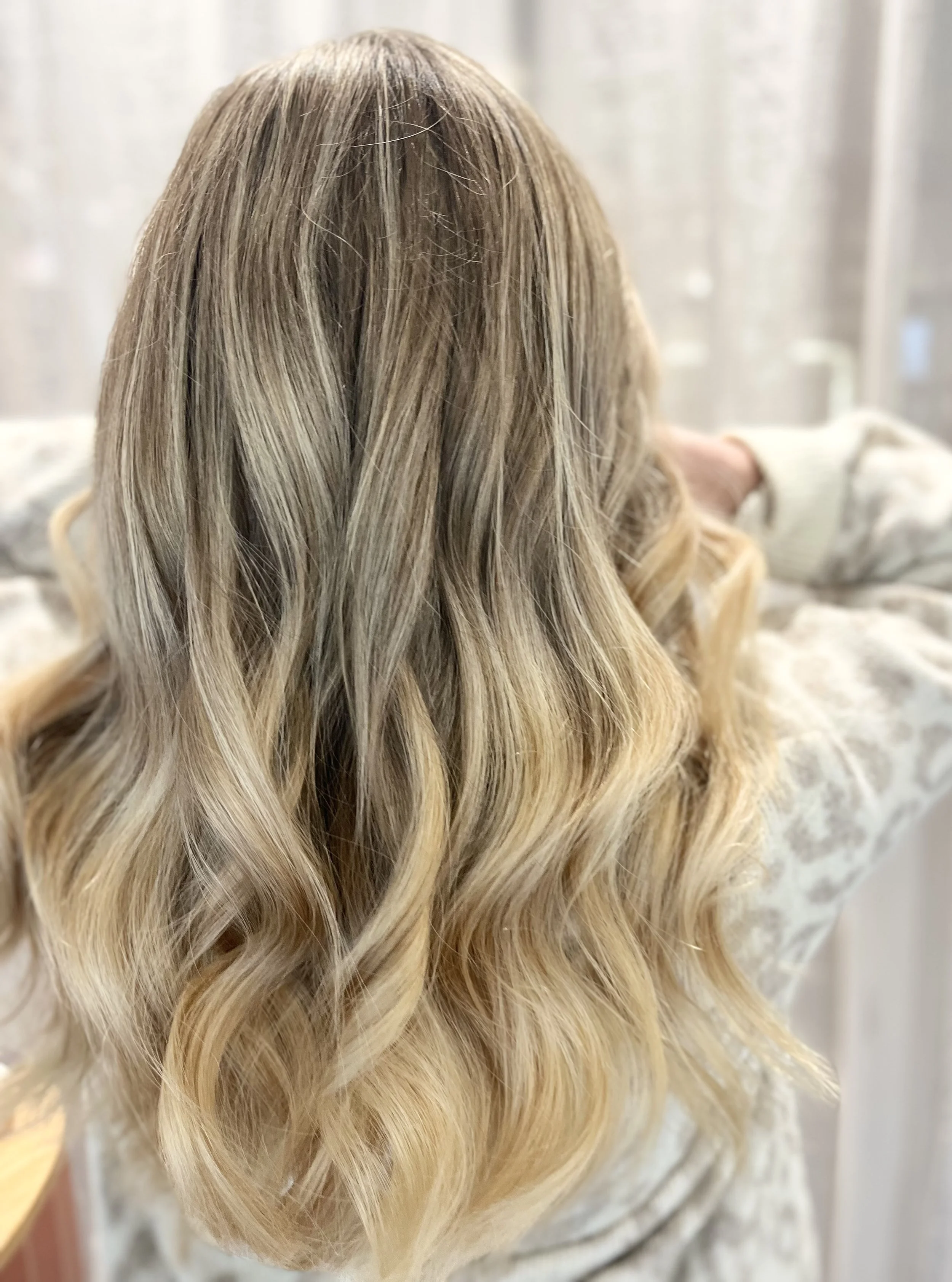 Blondiertes Haar mit blonden Strähnen einer modernen Strähnentechnik, Balayage  und lockigem Styling. Friseur in Esslingen am Neckar. Spezialist für Haarfarbe, Farbverläufe, Balayage und Extensions in Esslingen.