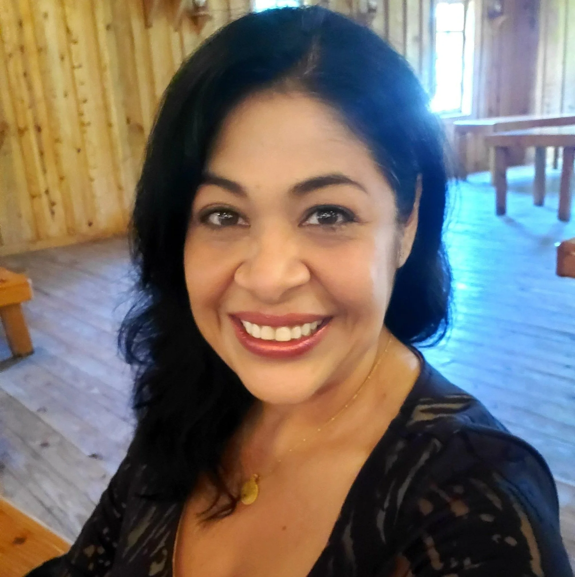 Sandy Brooke smiling in a warm rustic setting