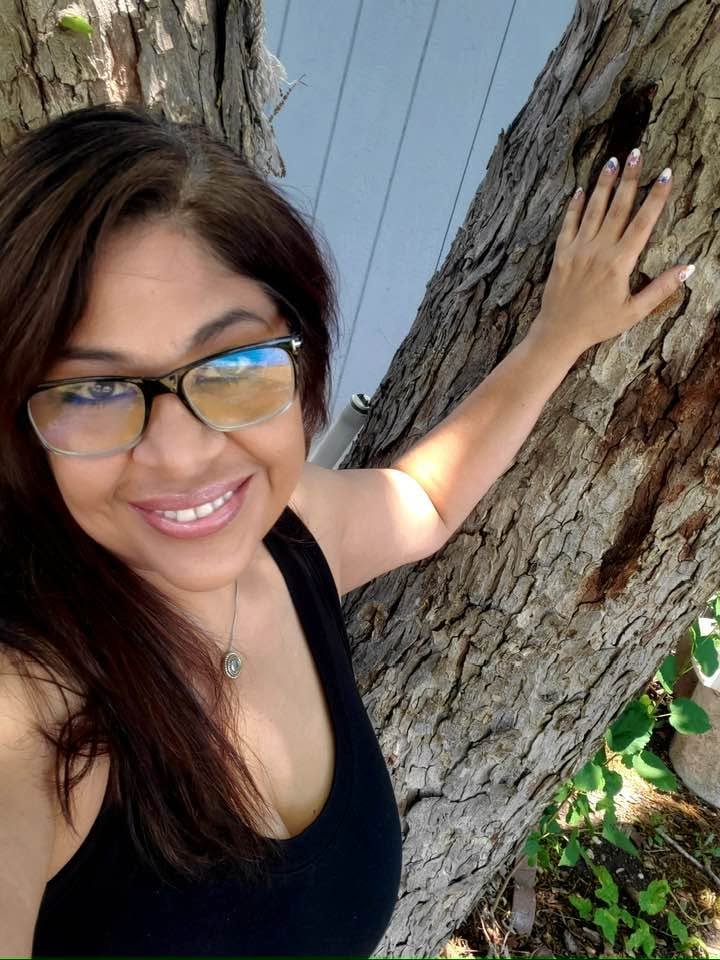 Sandy Brooke Martinez outdoors, leaning against a tree