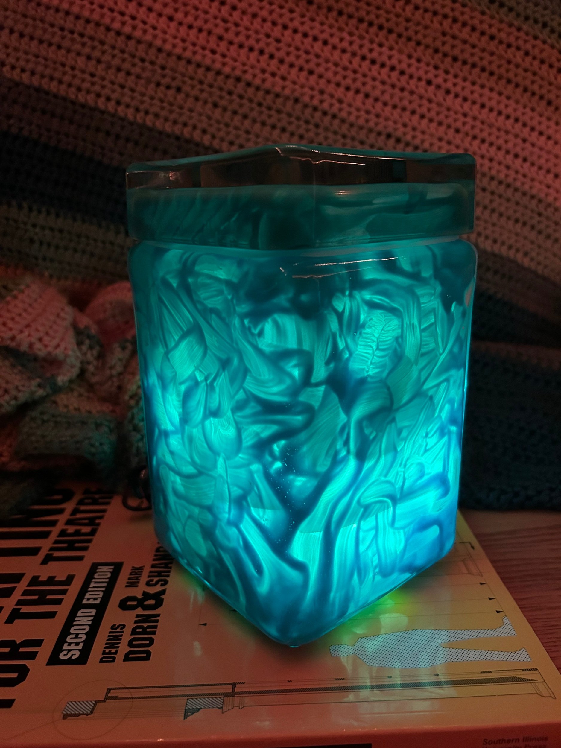 Scenery/Props 2023, Found object project. This is my rendition of the Tesseract from Marvel. I used a glass jar I found at Goodwill and painted the inside with acrylic paint and Mod Podge. I then put some scrap fabric and LEDs into the jar.