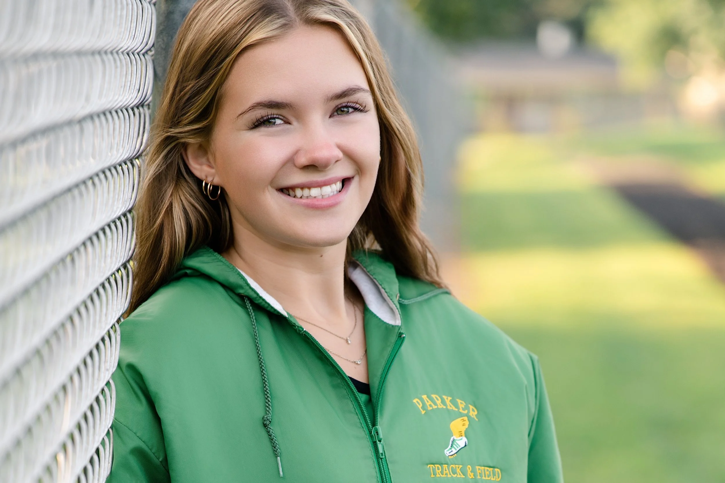 Parker High School senior posing for a portrait in her track warm-up jacket