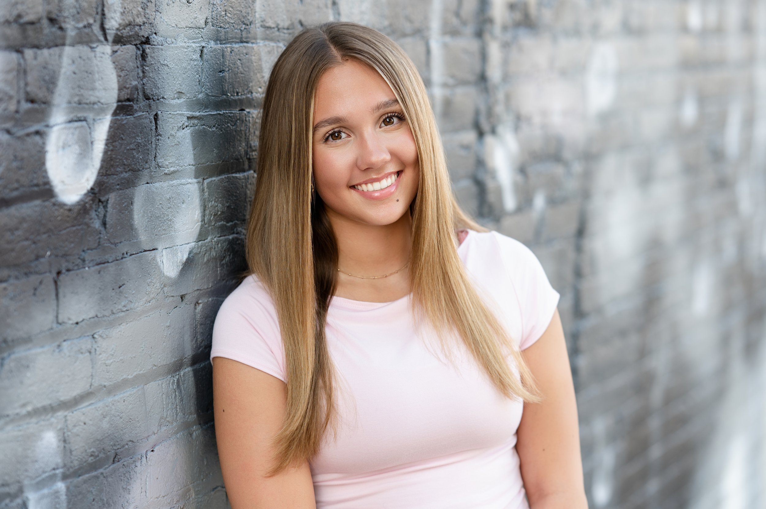 Urban senior portrait shoot with teen smiling in downtown Janesville, WI
