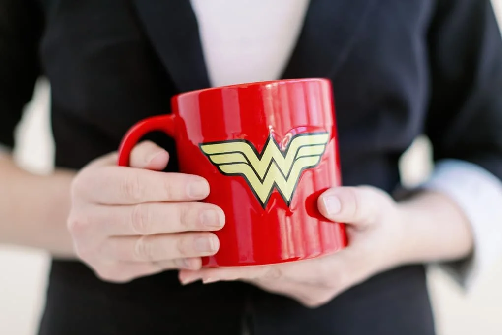Close up image of a red mug with the yellow Wonder Woman symbol.