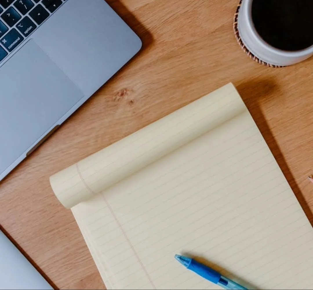 Flatlay image of a desk with an open laptop and a yellow notepad