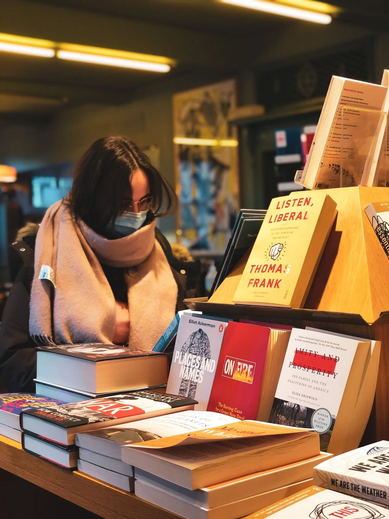 Person wearing a mask and browsing a table at a bookstore