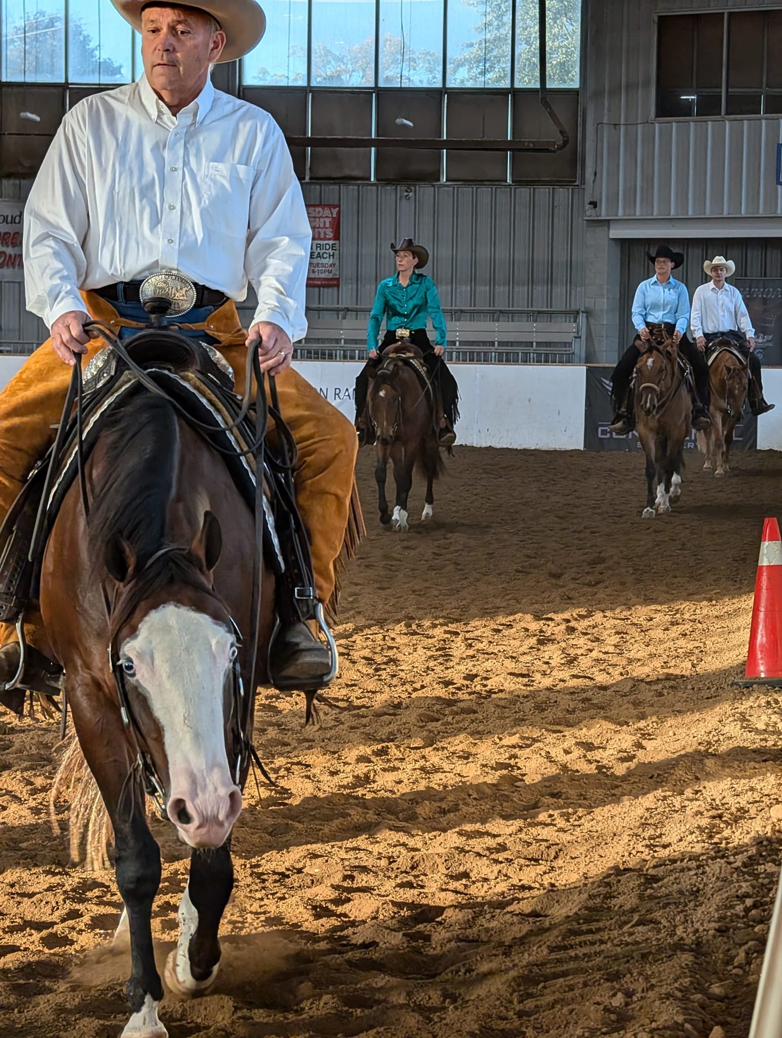 Group of people on horseback at indoor riding venue