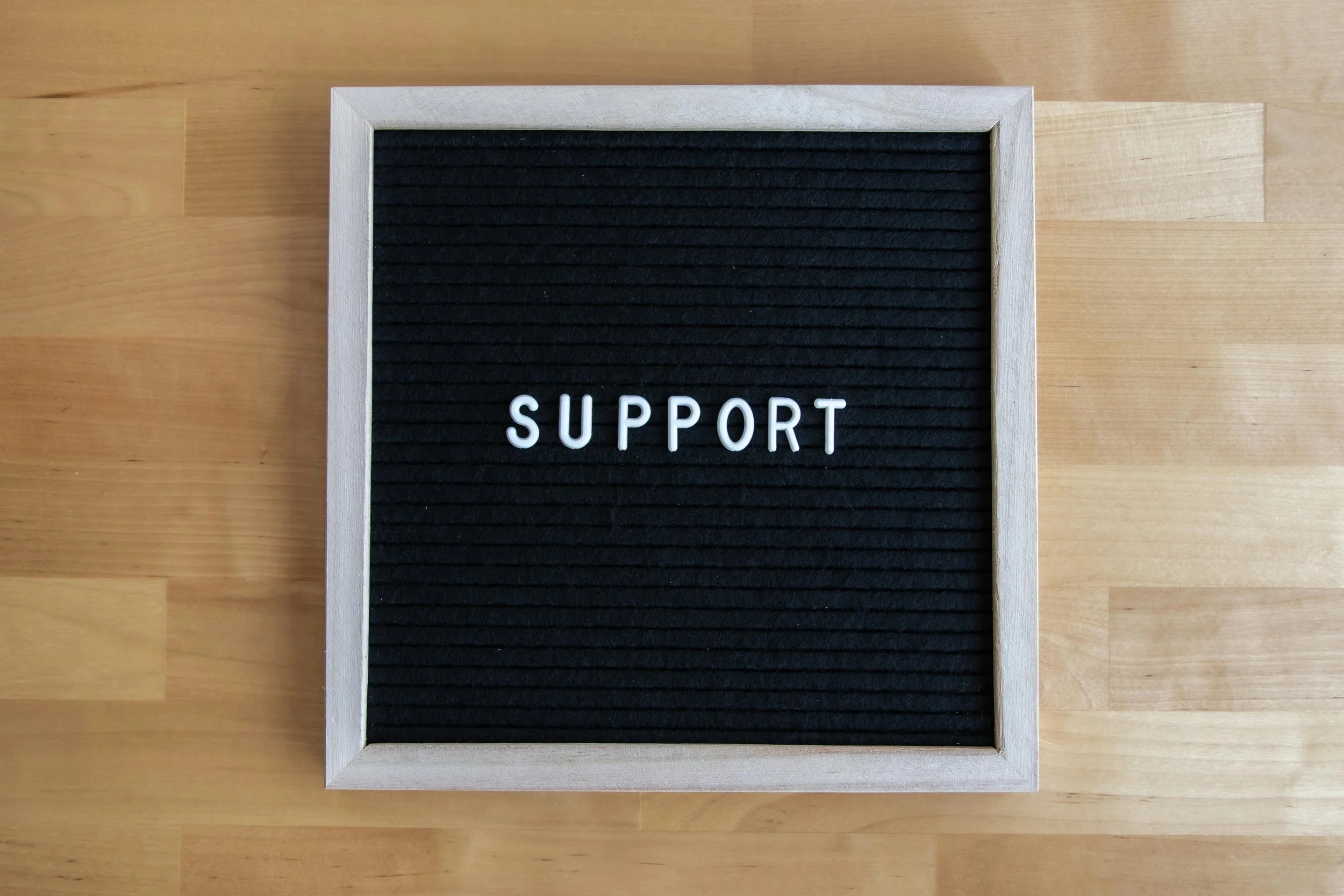 White-and-black-text-board-spelling-"support"