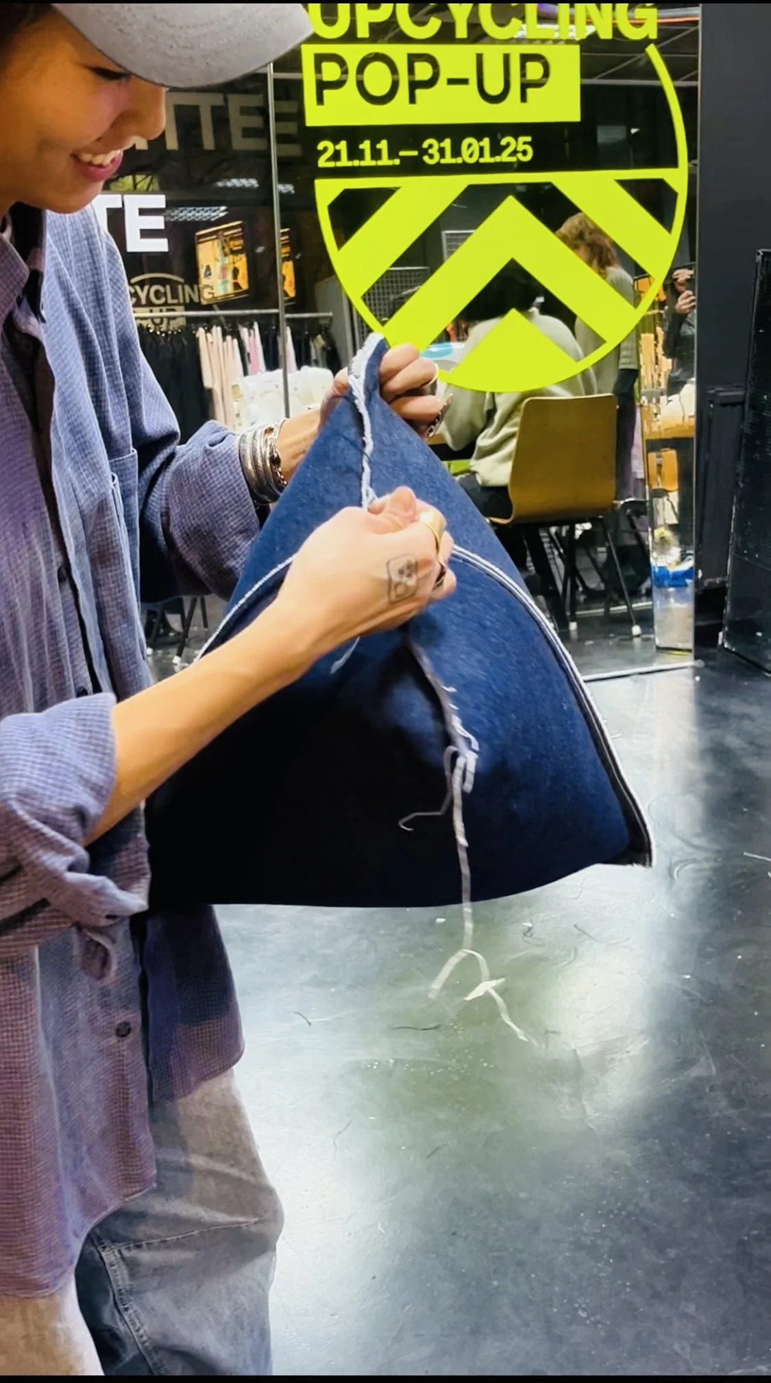 Person crafting a denim pillow at an upcycling pop-up event.