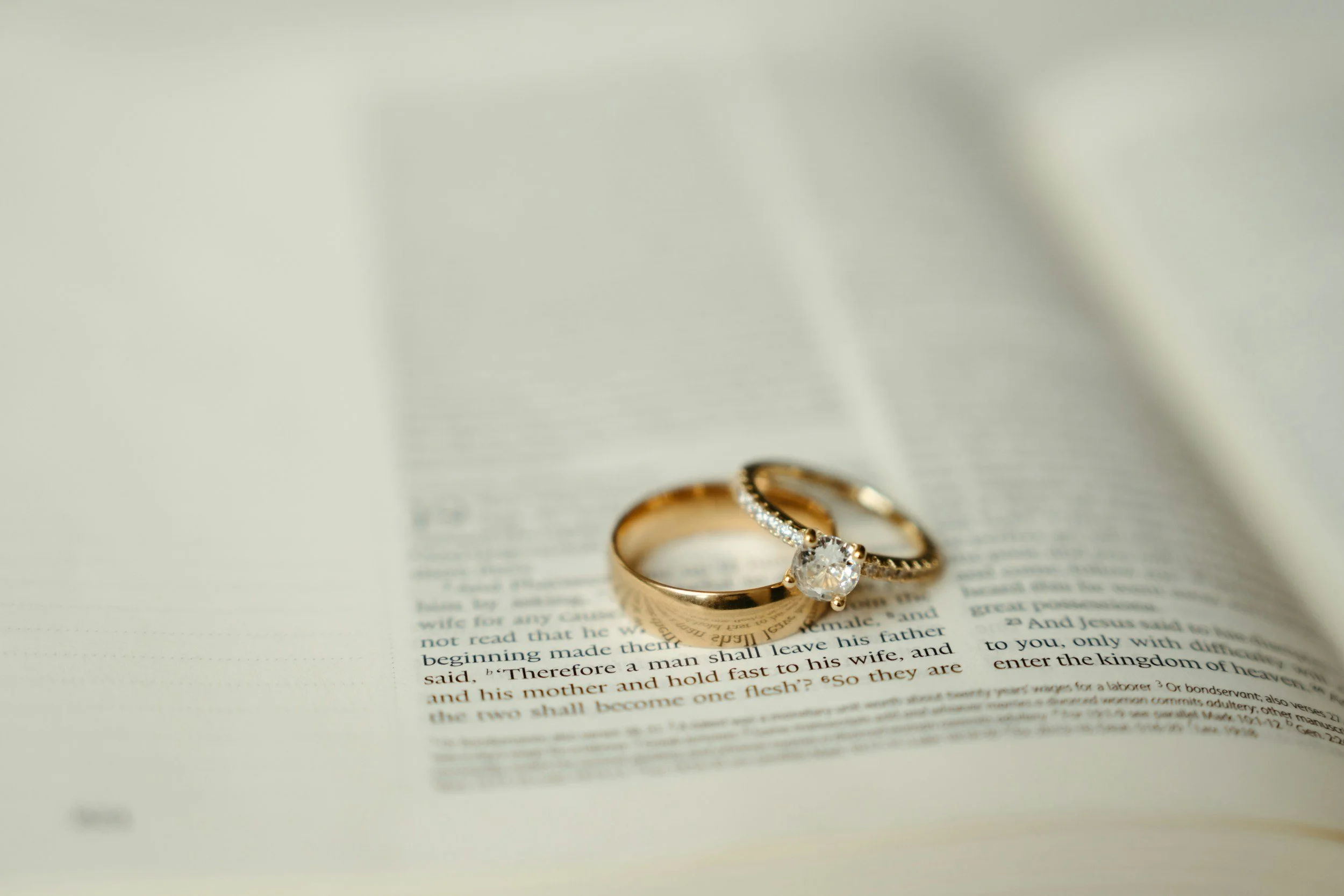 Close-up of two gold rings with a large gemstone on an open book.