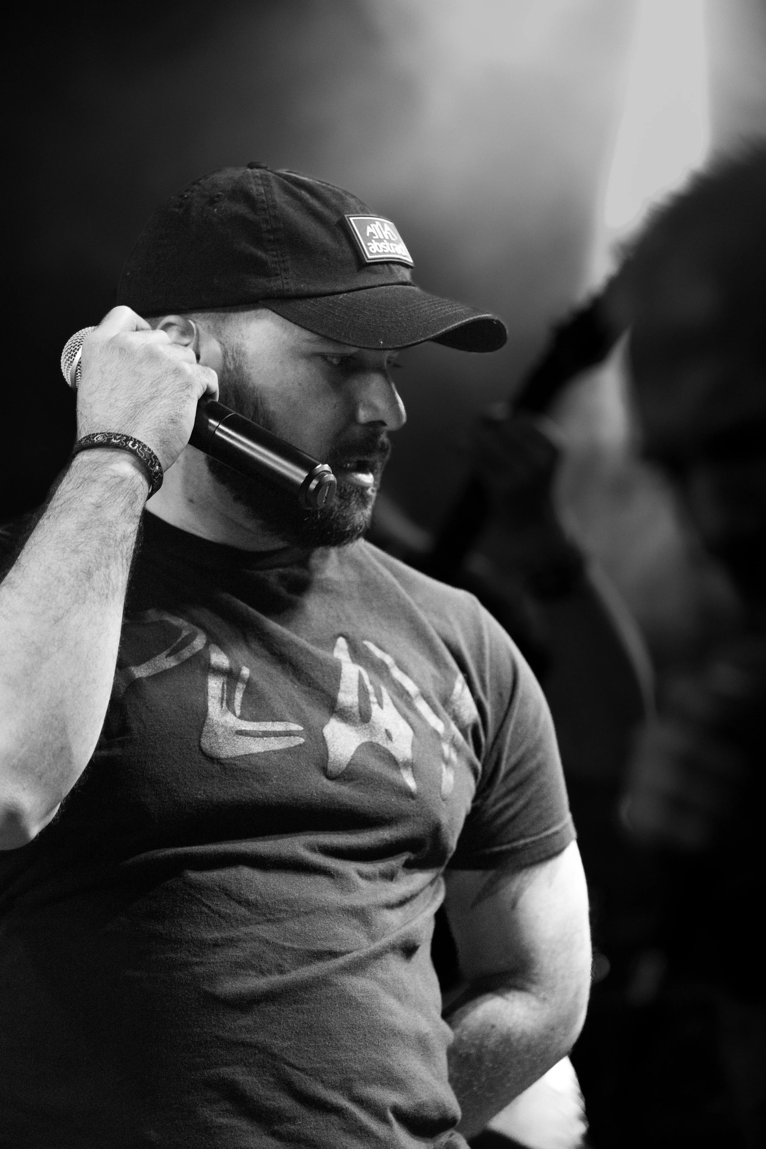 Front man singer of Shotgun Opera wearing a cap and headphone holding a microphone.