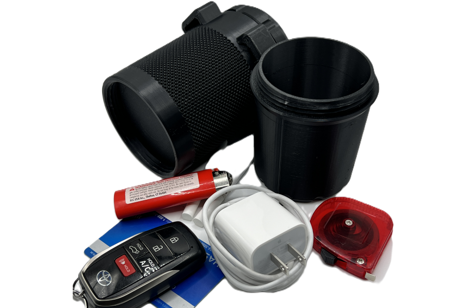 A collection of miscellaneous objects including a black flashlight, a black plastic cup, a red and white battery, a white charger, a car key with buttons, and a small red and clear warning light.
