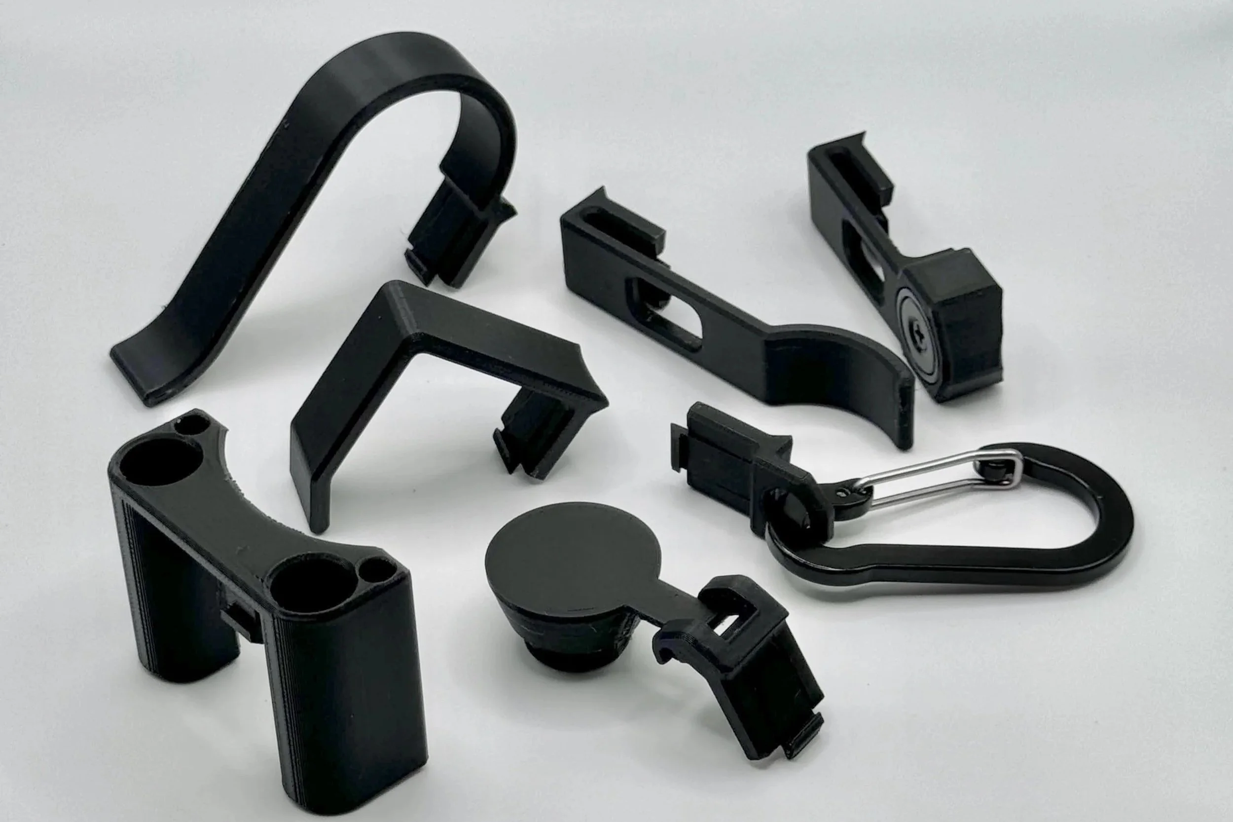 Collection of black Clix, which are accessories for Tacti-can drink cooler/coozie.