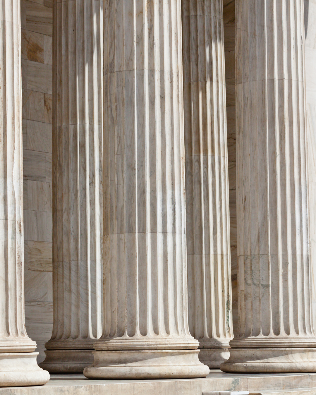Close-up of multiple large marble columns with fluted design, part of a classical building.