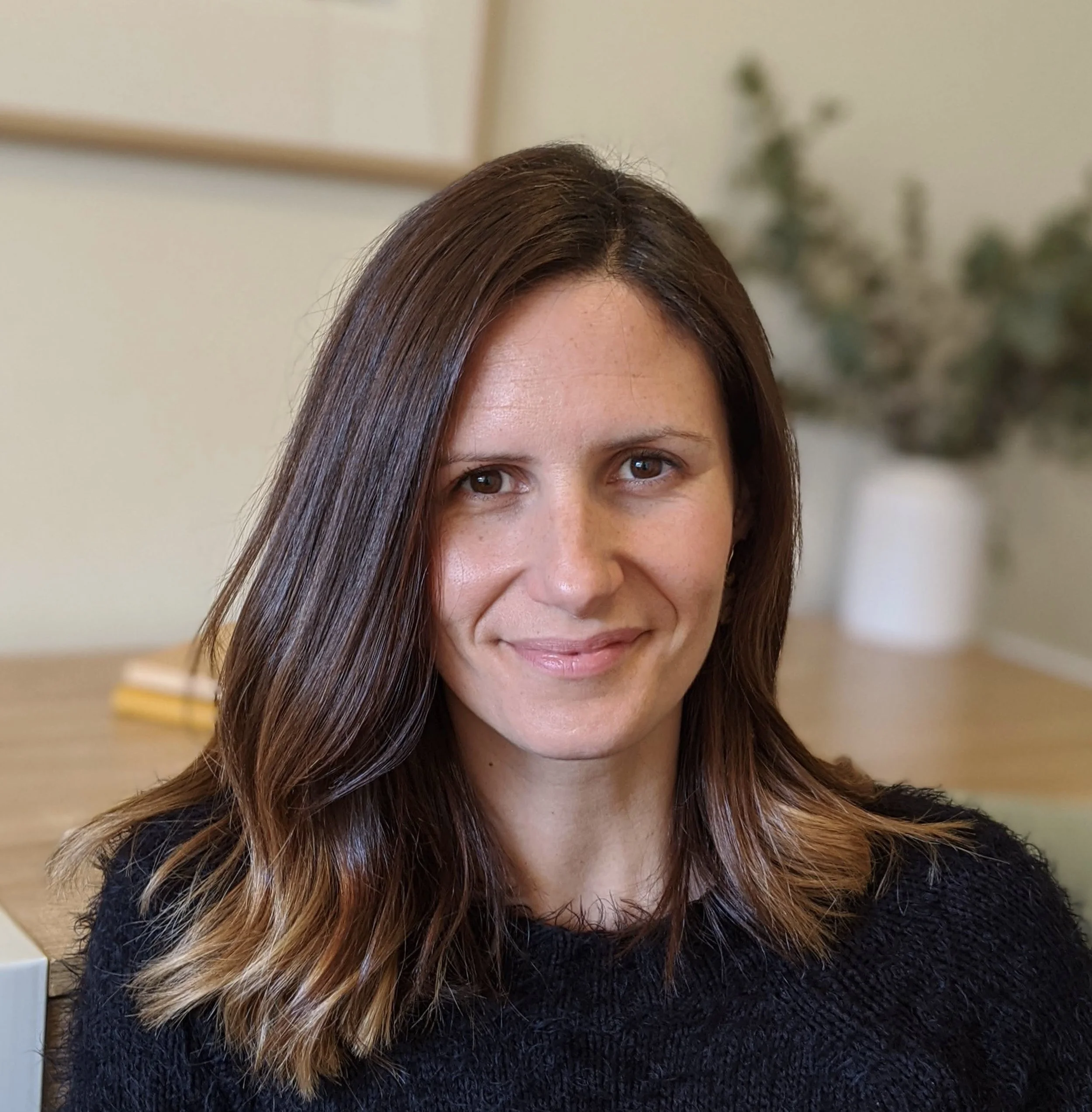 Sonia Dempsey in a home office setting with a plant and books in the background.