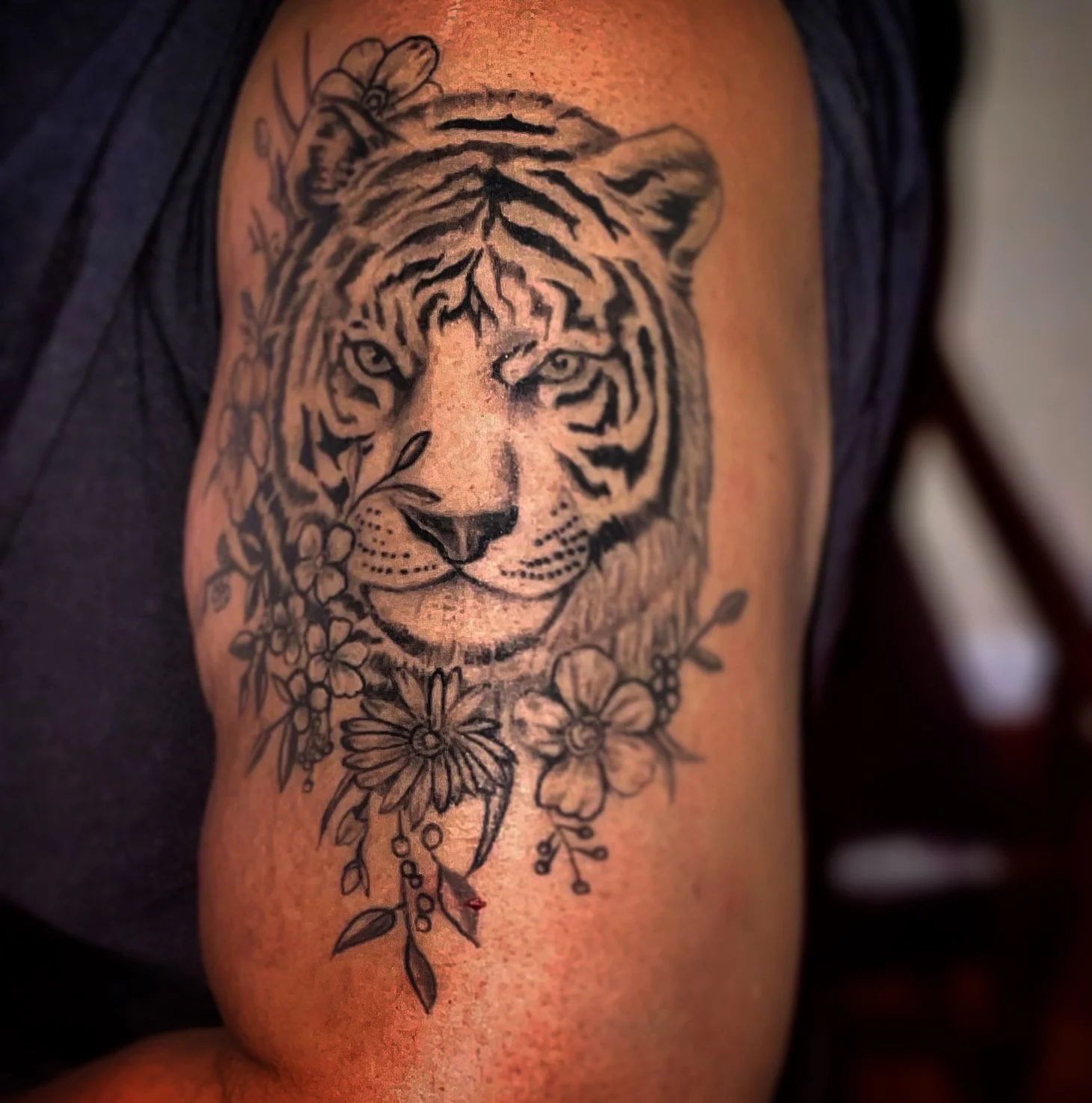 Tattoo of a tiger with floral designs on upper arm