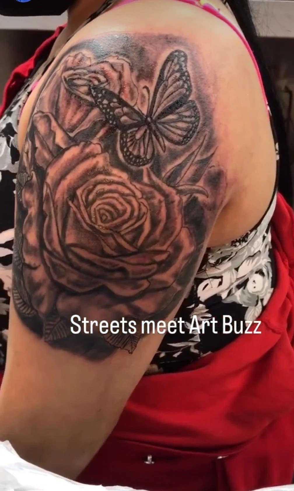 Tattoo of roses and butterfly on arm with "Streets meet Art Buzz" text.