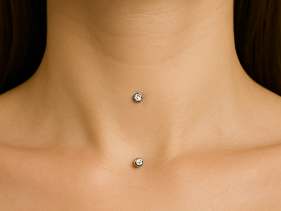 Close-up of a person's neck with two diamond stud piercings.