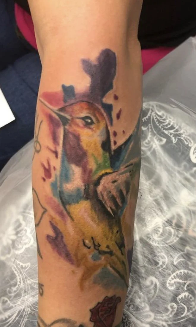 Colorful hummingbird tattoo on forearm with abstract elements.