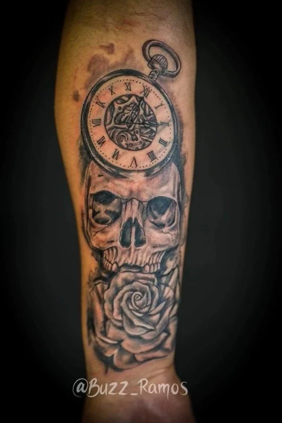 Tattoo featuring a skull, pocket watch, and rose on forearm