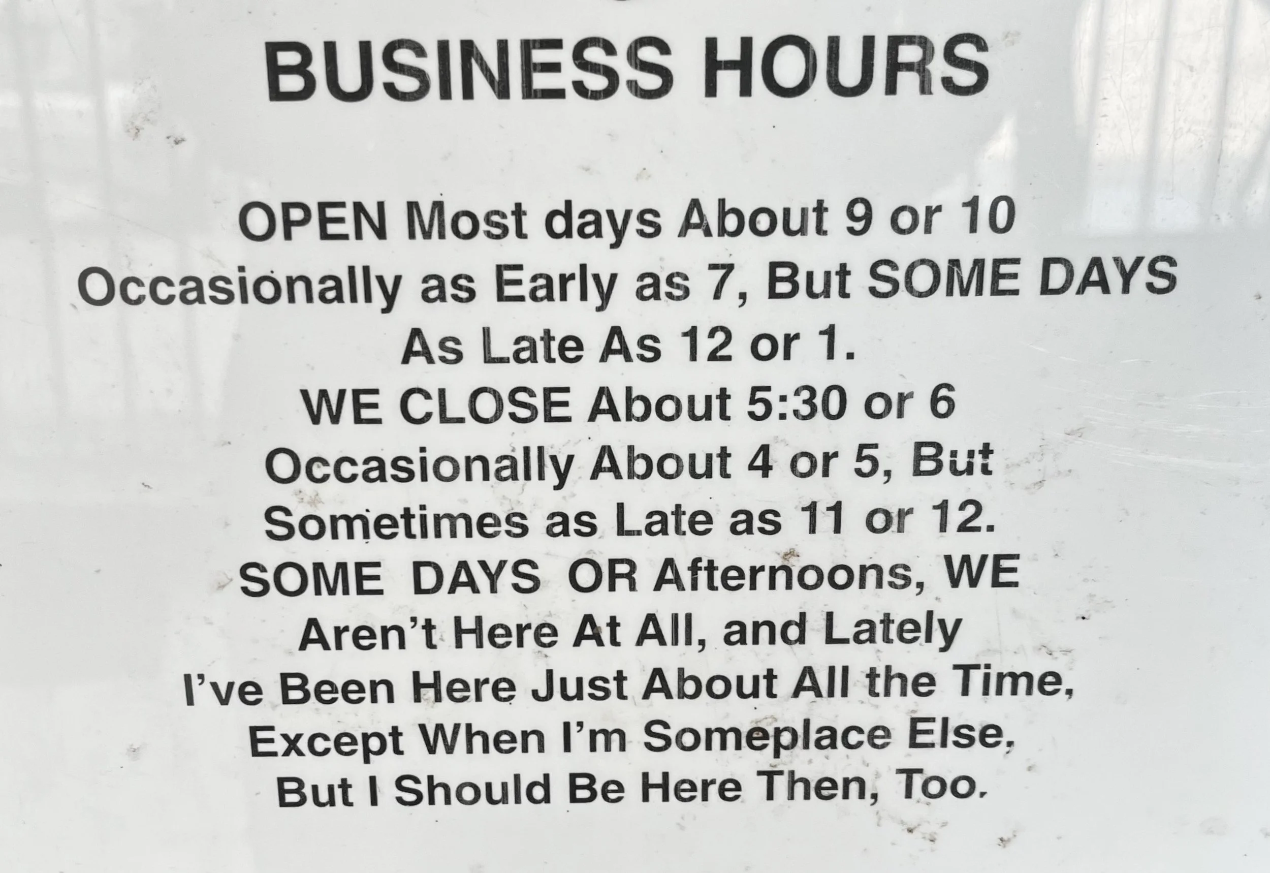 Sign with business hours information, indicating open most days around 9 or 10 AM, occasionally as early as 7, but sometimes as late as 12 or 1 PM. The business closes about 5:30 or 6 PM, sometimes as early as 4 or 5, but occasionally as late as 11 or 12 PM. The sign notes that they are not always there at all and have been present most of the time, except when elsewhere.