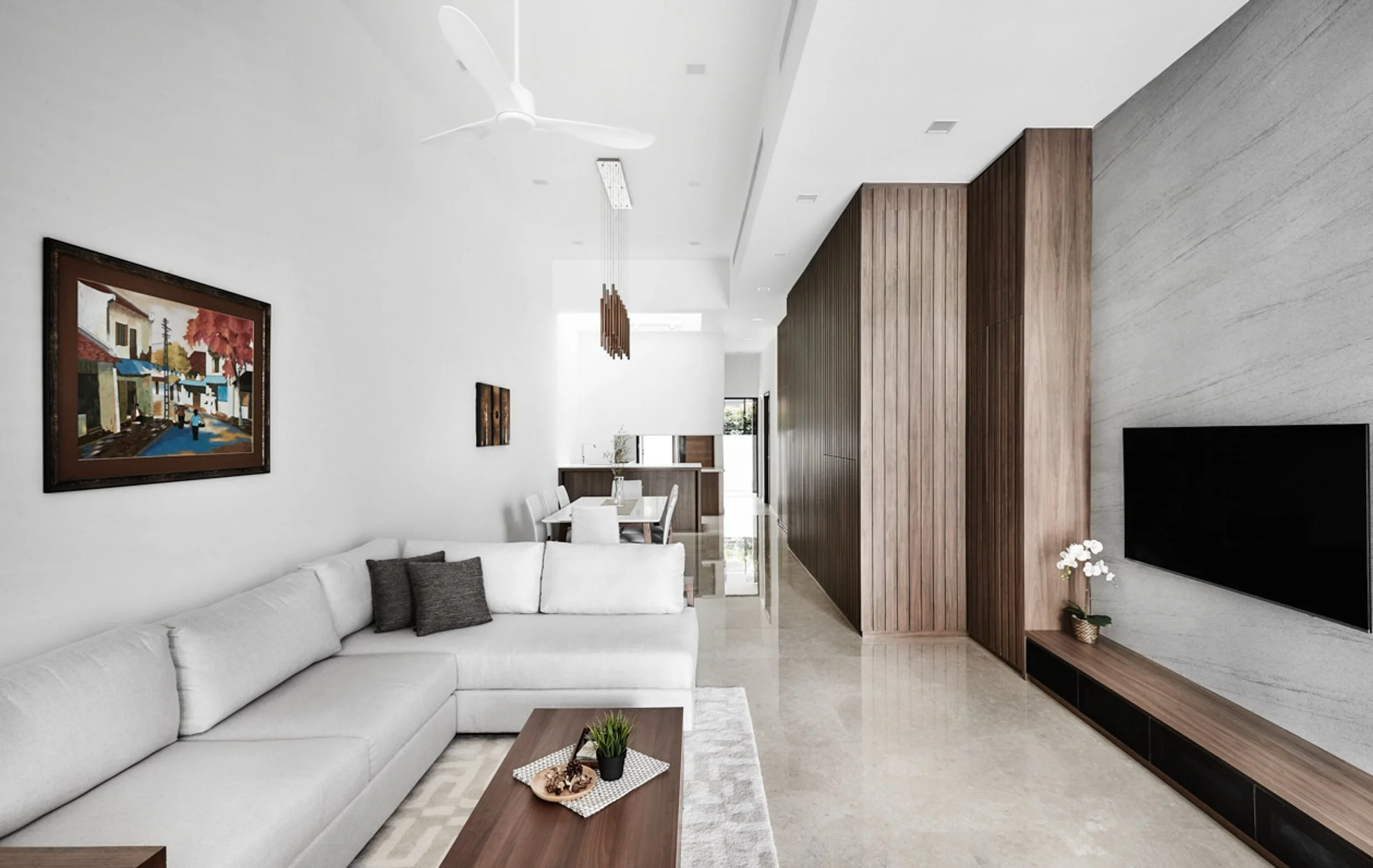 Contemporary Modern living room of a 5 storey landed home in Singapore, Bukit Timah, with a white sectional sofa, stone tv feature wall, fluted panel feature wall, and dining area in the background. There is a ceiling fan on the high ceiling.