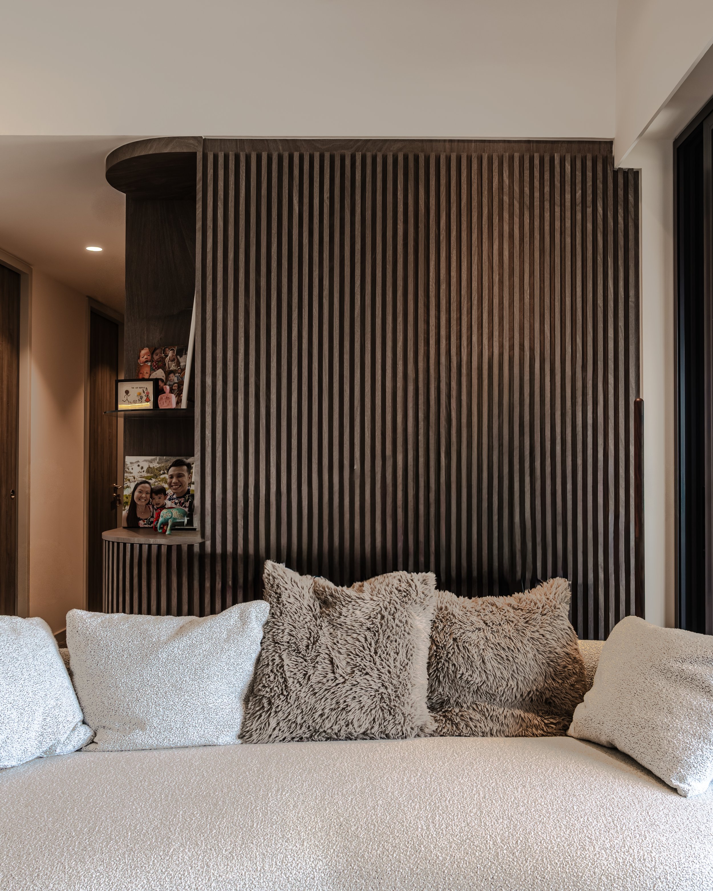 Beyond Japandi interior design in a Singapore home: a serene 'Slow Living' space with vertical wood fluting, organic curved shelving, and layered earth-toned textiles, illustrating the 2026 rise of Warm Minimalism."