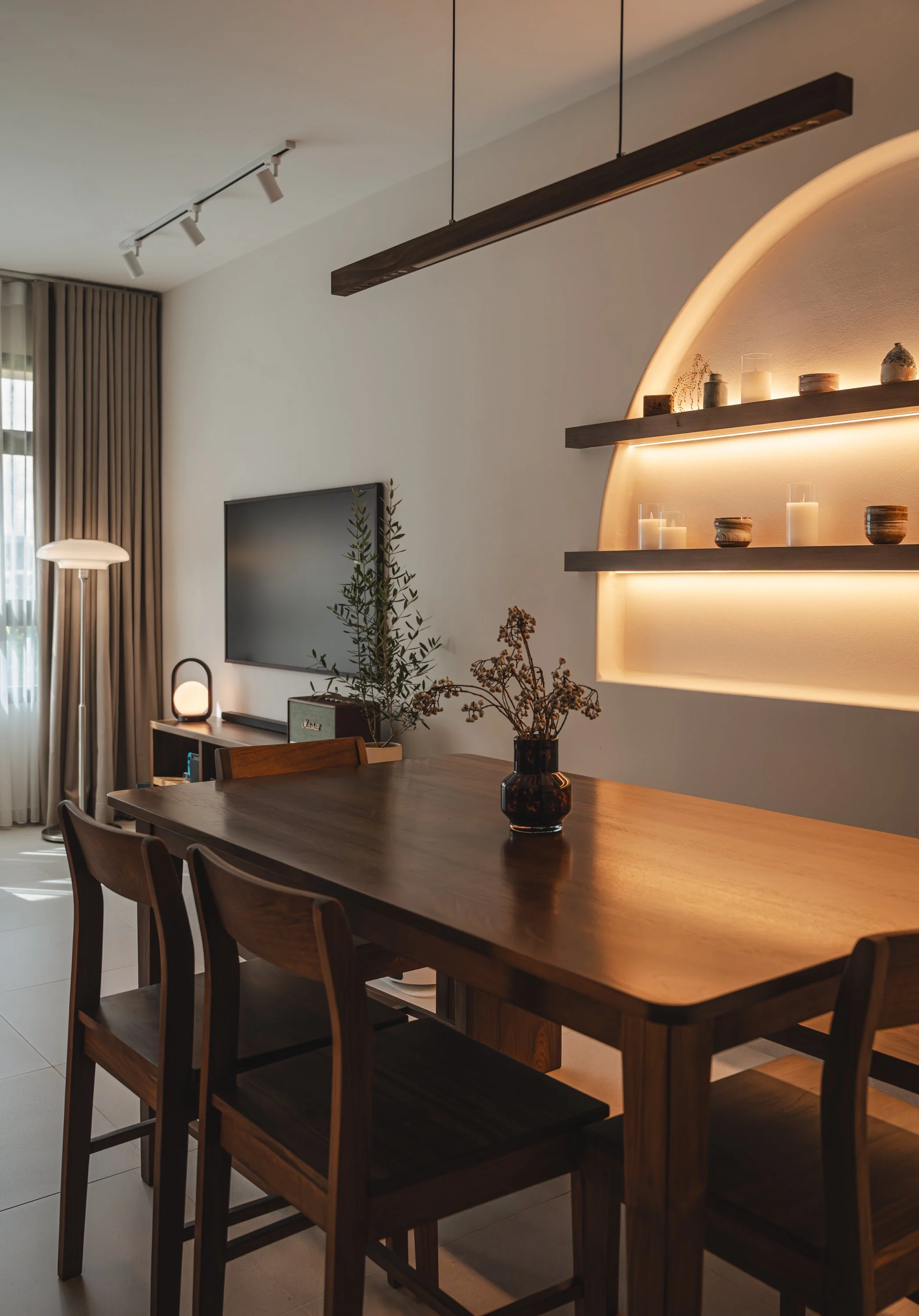 Mid Century Modern BTO  interior living room with wooden table and chairs, arched wall design & shelf with candles and vases display, TV with no feature wall, and floor lamp design