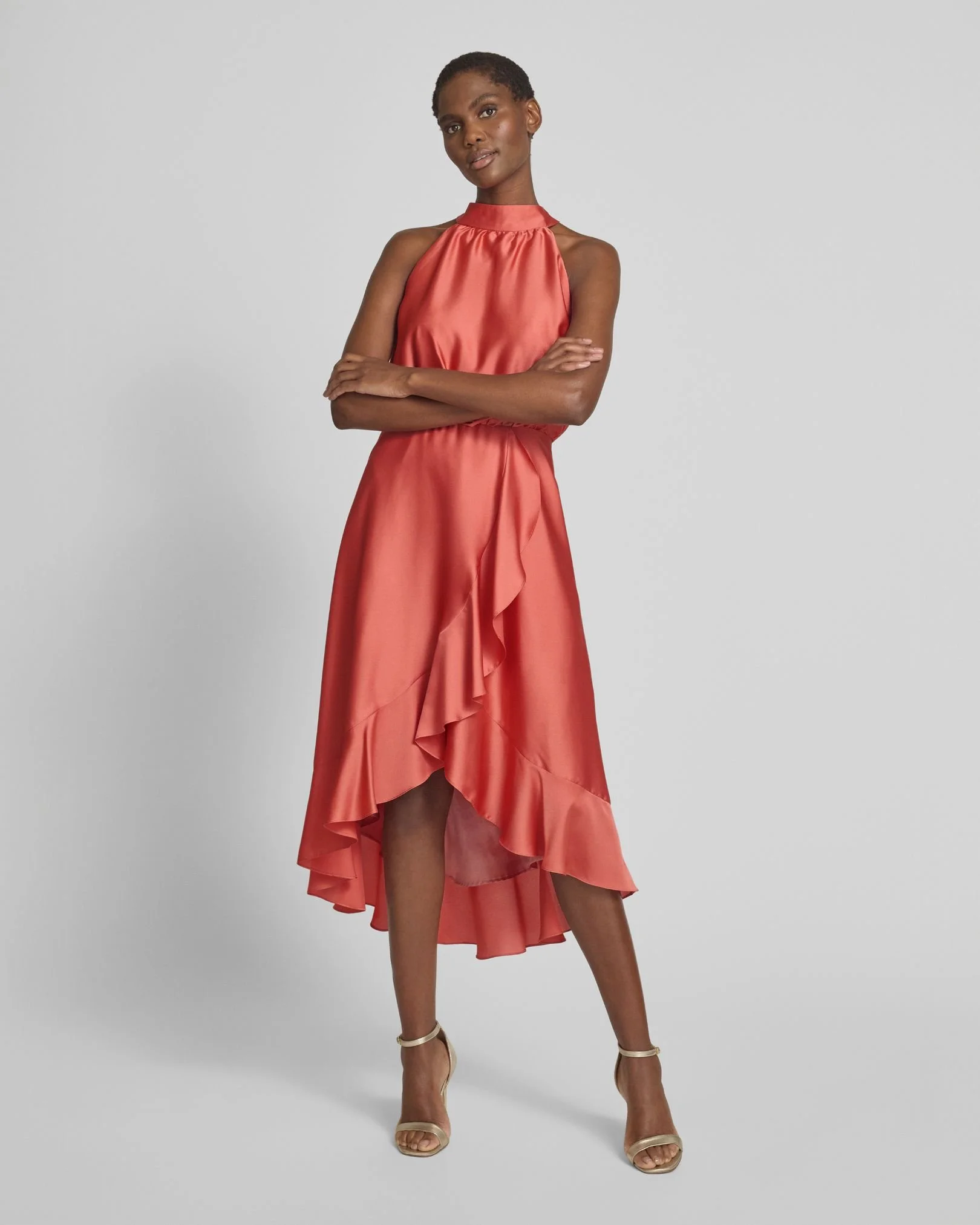 Frau trägt ein rotes, ärmelloses, rüschenbesetztes Kleid und hohe Sandalen