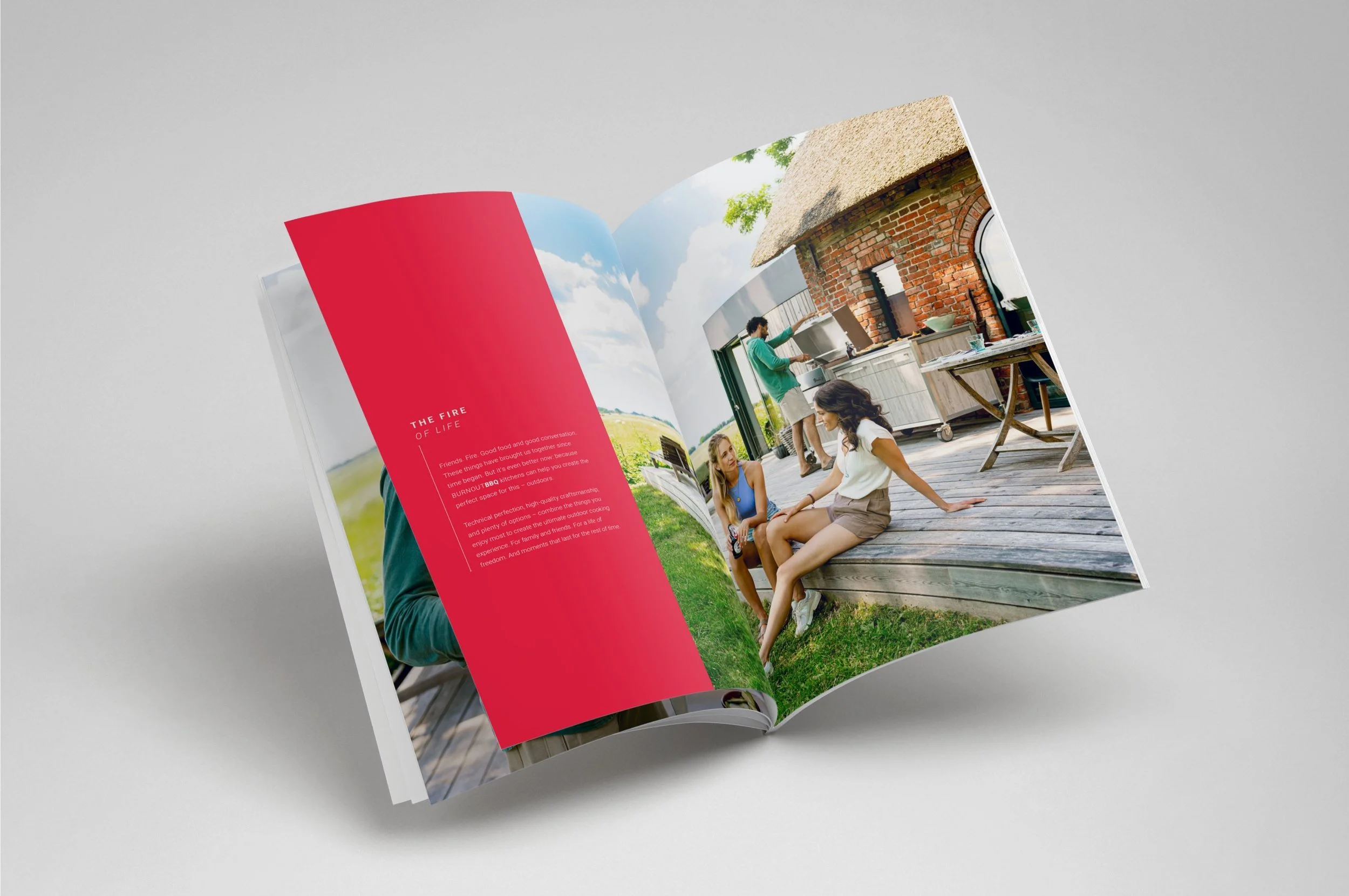 Offener Fotoband mit einem Bild von drei Frauen auf einer terrakottafarbenen Veranda, im Hintergrund eine Frau in Mint-Shirt beim Grillen, im Vordergrund zwei Frauen, die auf den Boden sitzen, eine in weißem Top und Shorts, die andere in Bluse und Shorts.