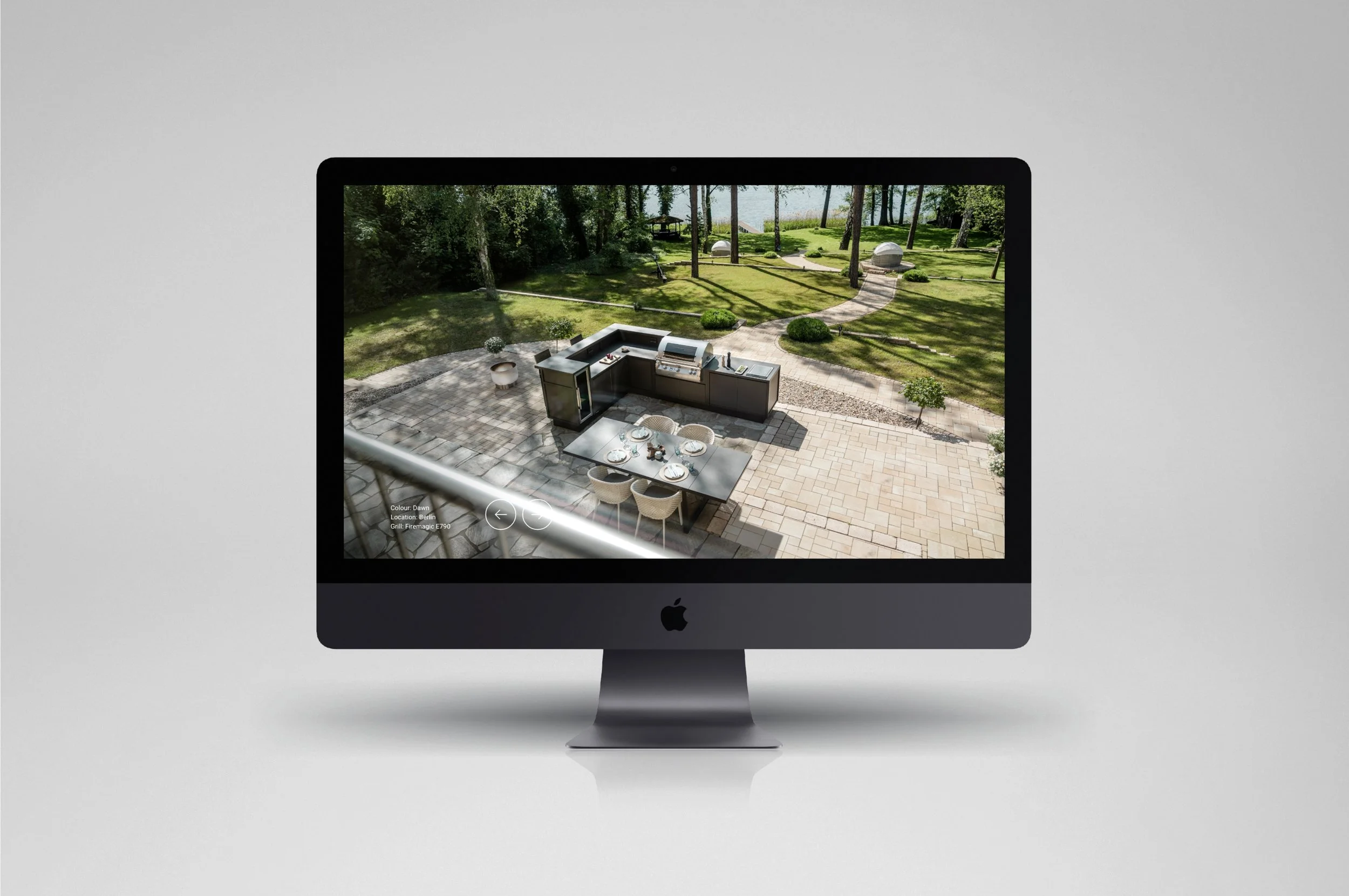 Ein iMac-Computer zeigt eine Überwachungskameraaufnahme eines Gartenbereichs mit Terrasse, Gartenmöbeln und grünem Rasen.