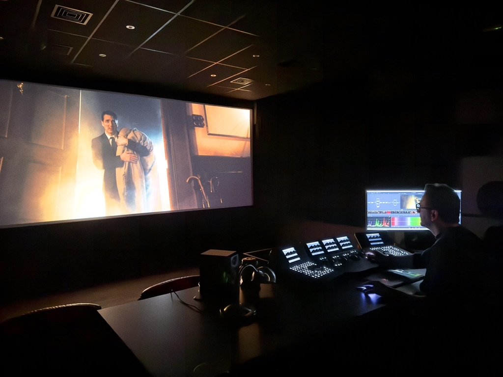 Colourist at a grading console facing a cinema screen