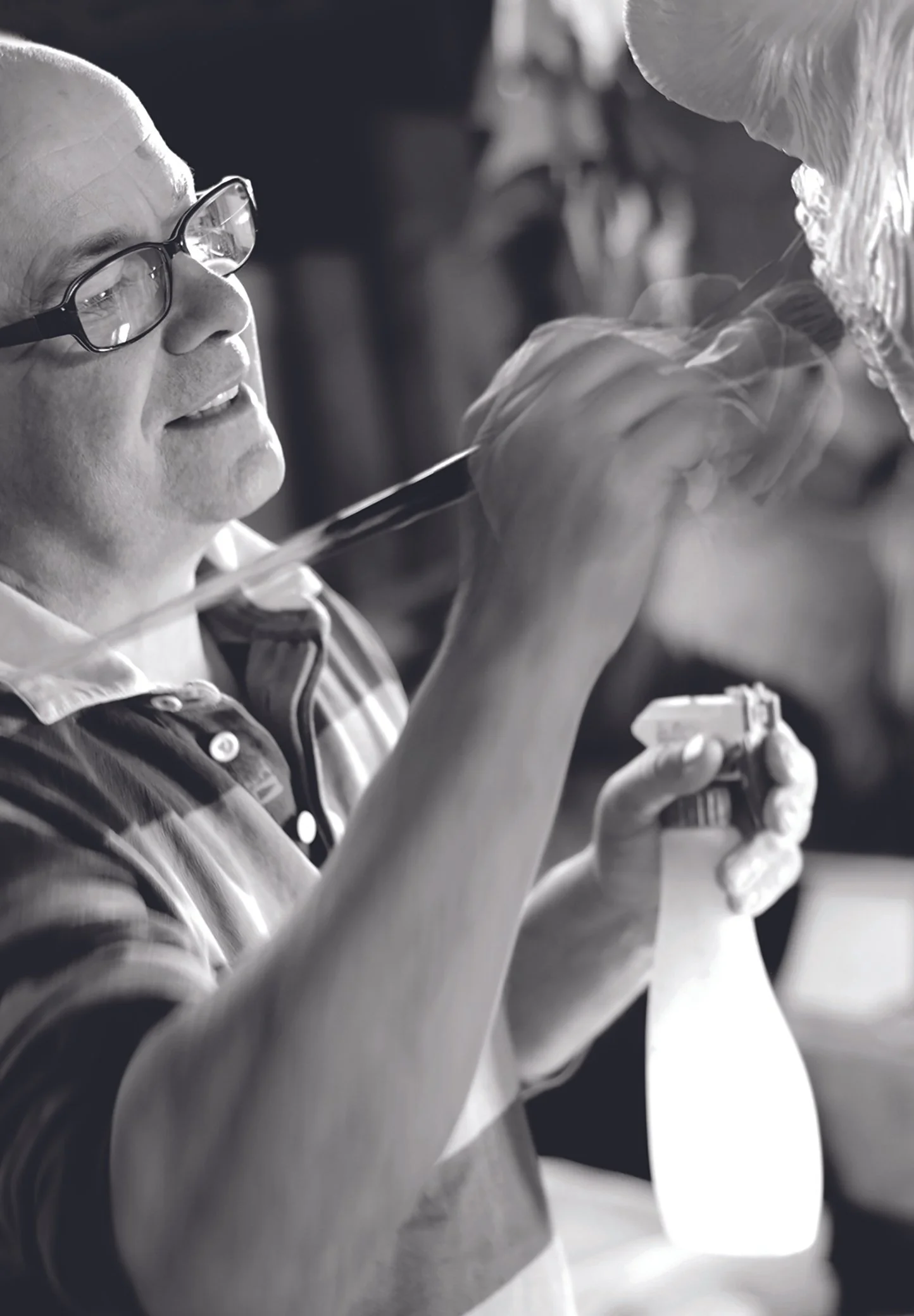 Artist painting with brush and spray bottle, black and white photo.