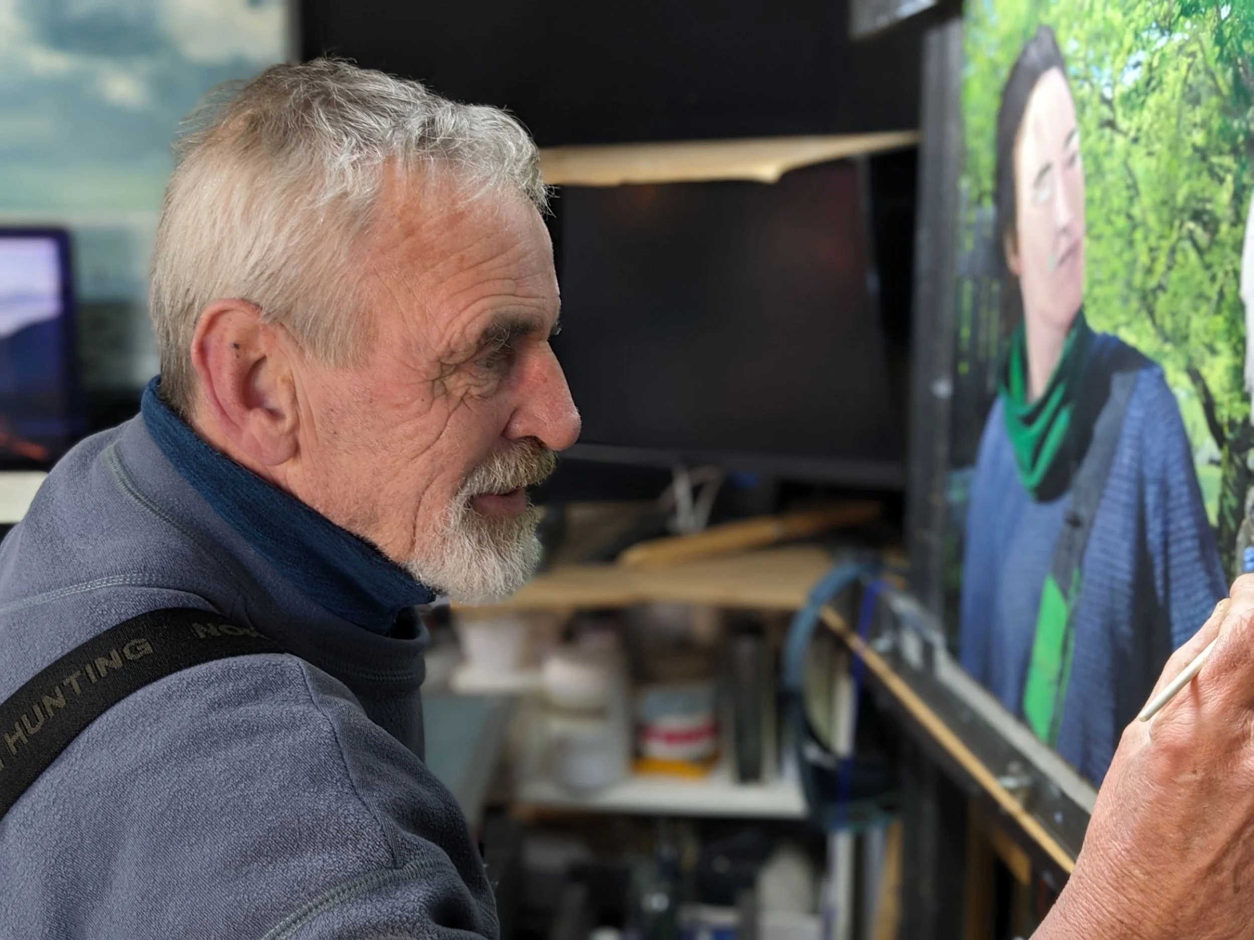 Older man painting on a canvas in an art studio.