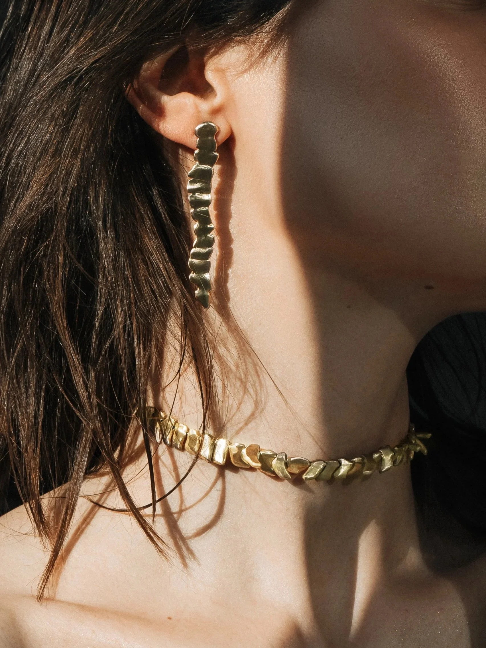 sculptural bronze choker with matching drop earrings worn on a model