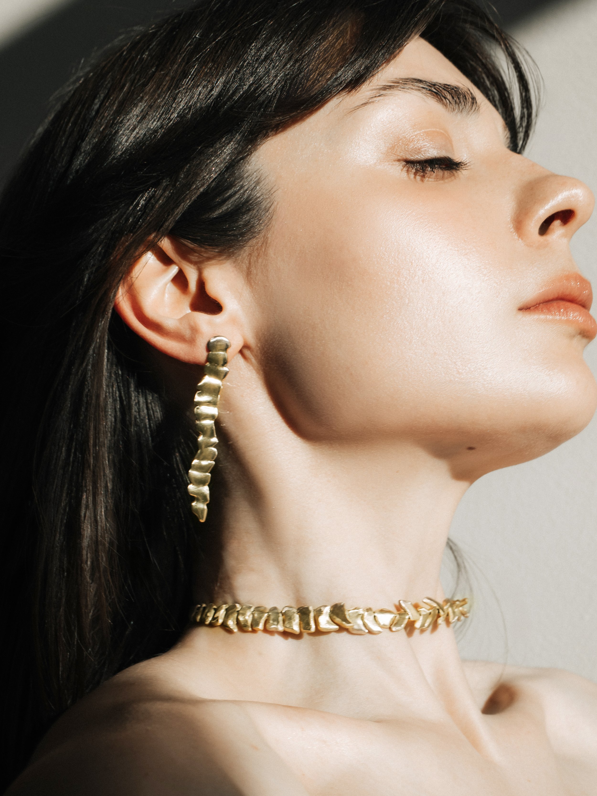 Sculptural bronze drop earring worn on a model