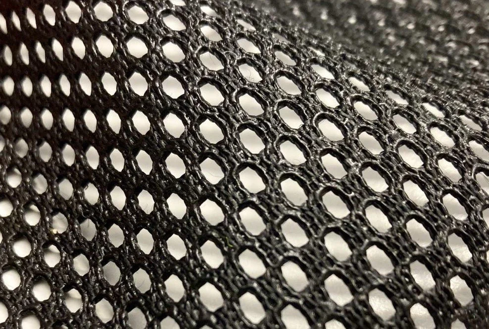 Nahaufnahme eines schwarzen Gittermaterials mit regelmäßigen Löchern.