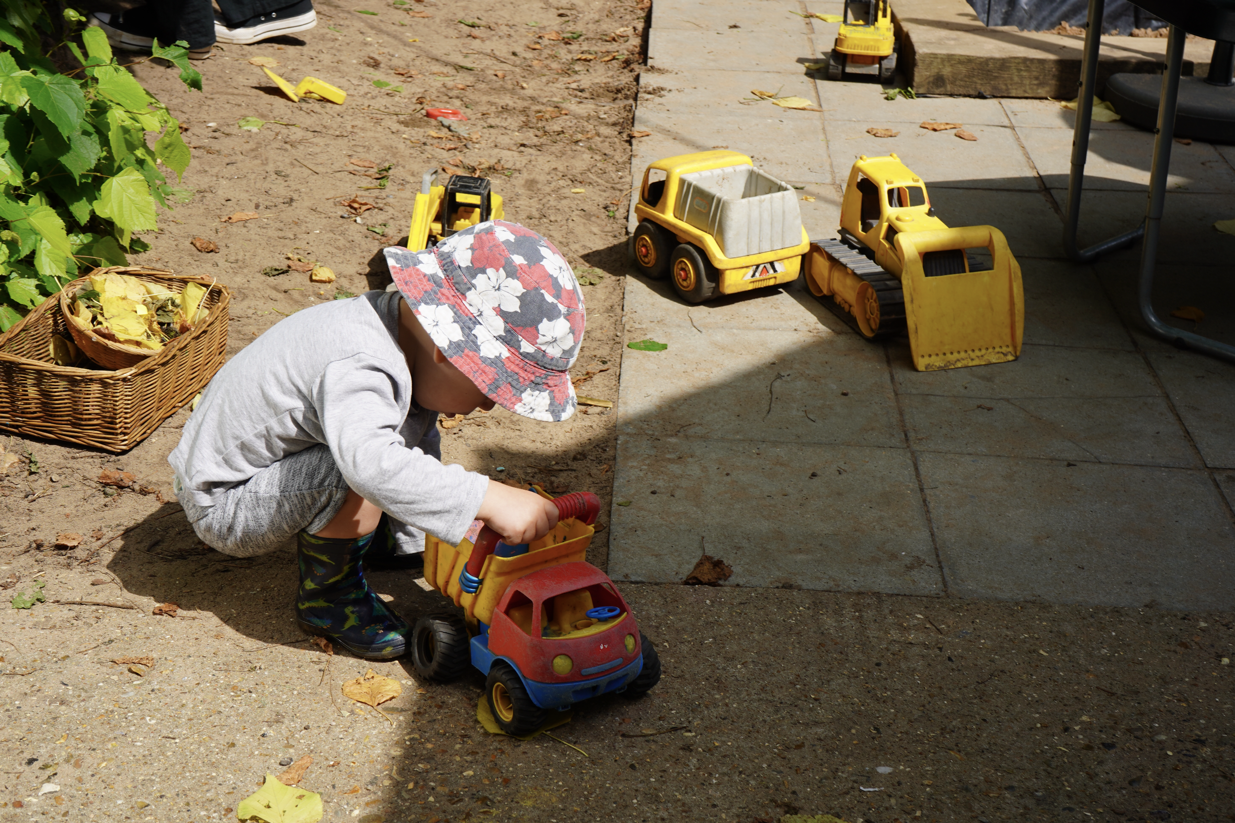 Child playing with toy construction vehicles outdoors at the Tadpoles Nursery Woodham Walter.