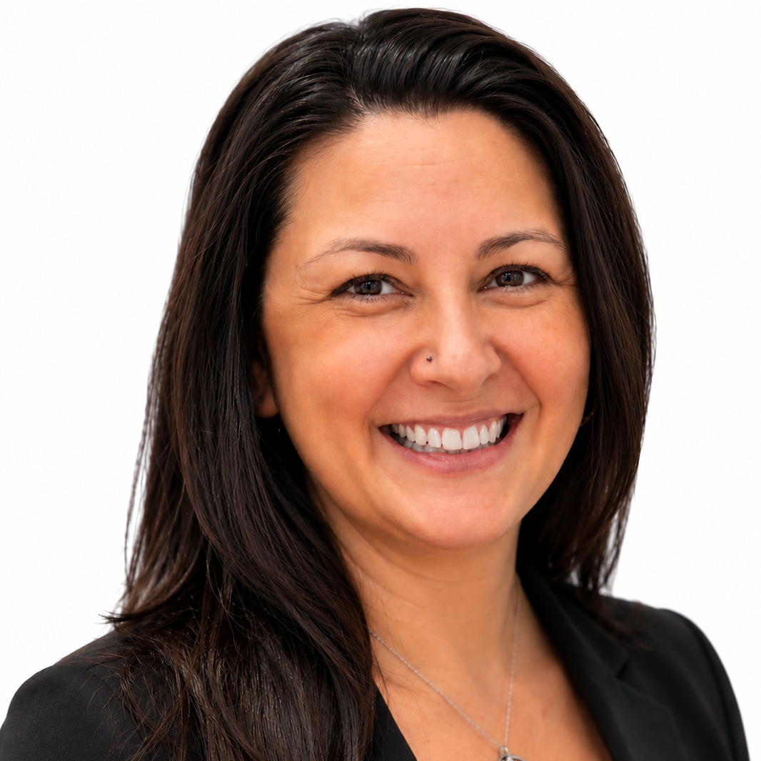 A woman with straight dark brown hair smiling at the camera in front of a gray background.