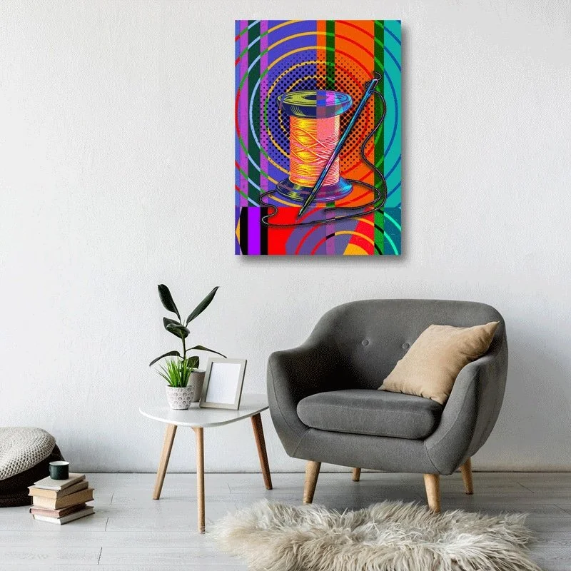 A colourful needle and thread print is displayed next to a grey armchair