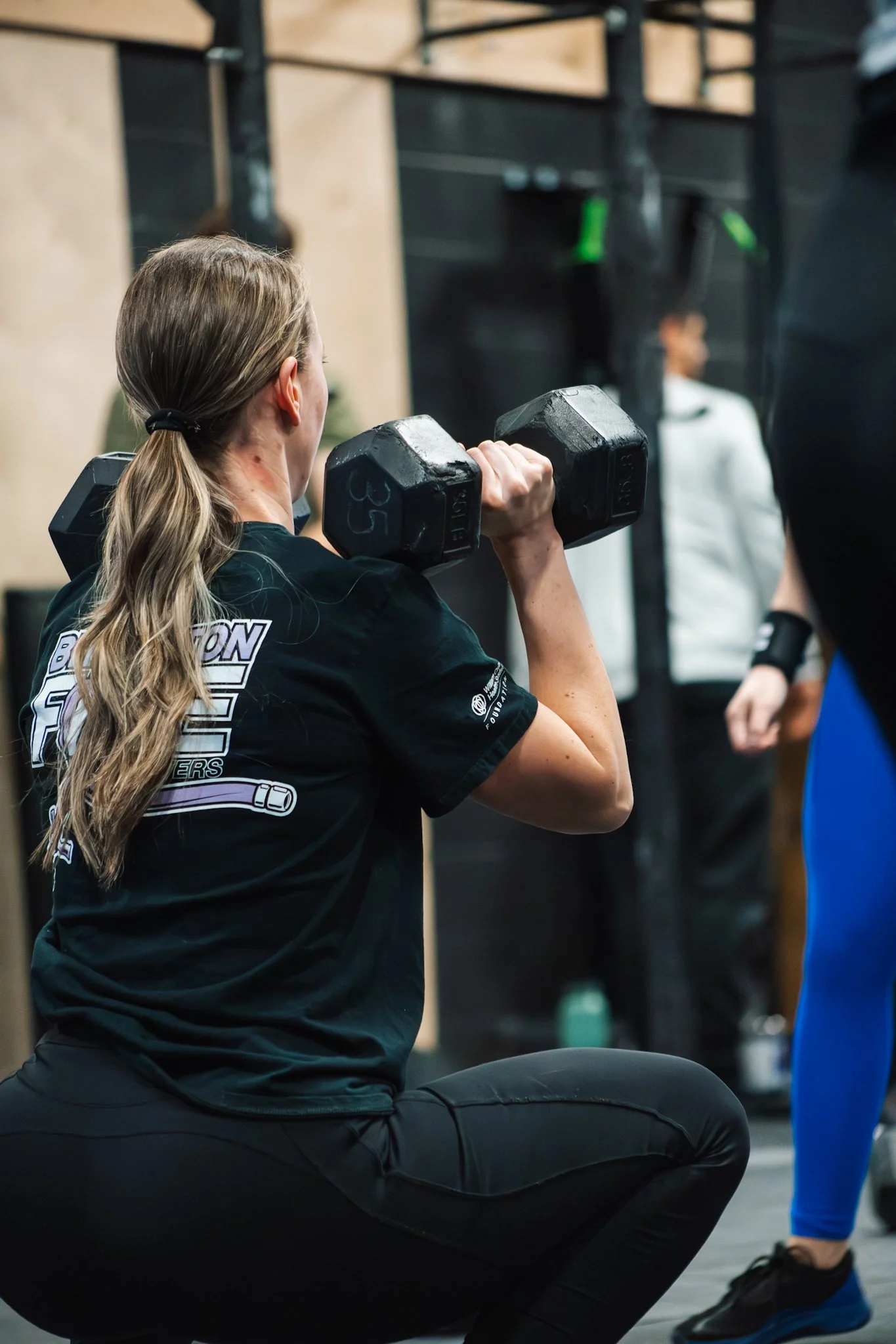 Woman doing a squat exercise with a dumbbell in a gym