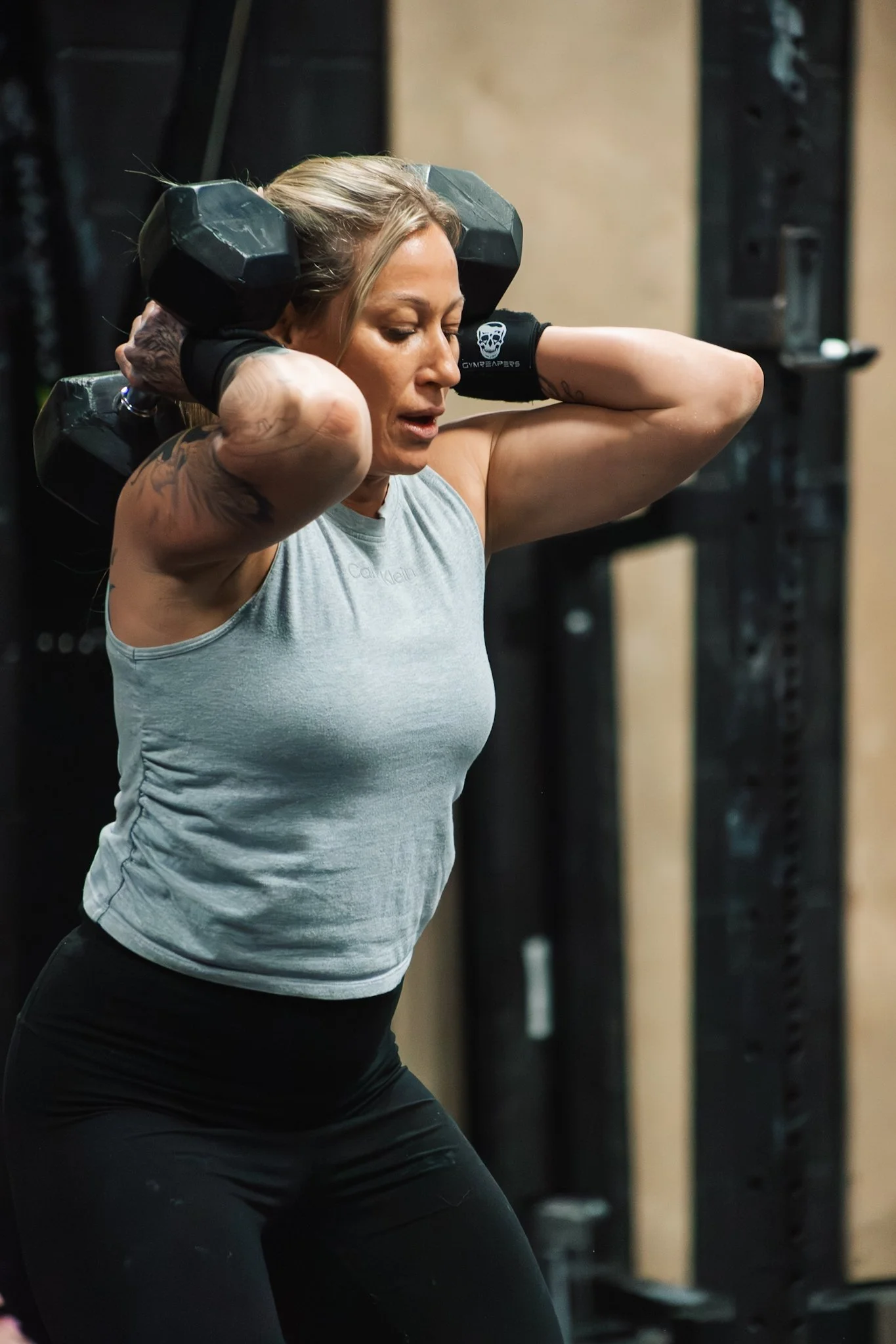 Woman lifting a dumbbell on her shoulders during a workout.