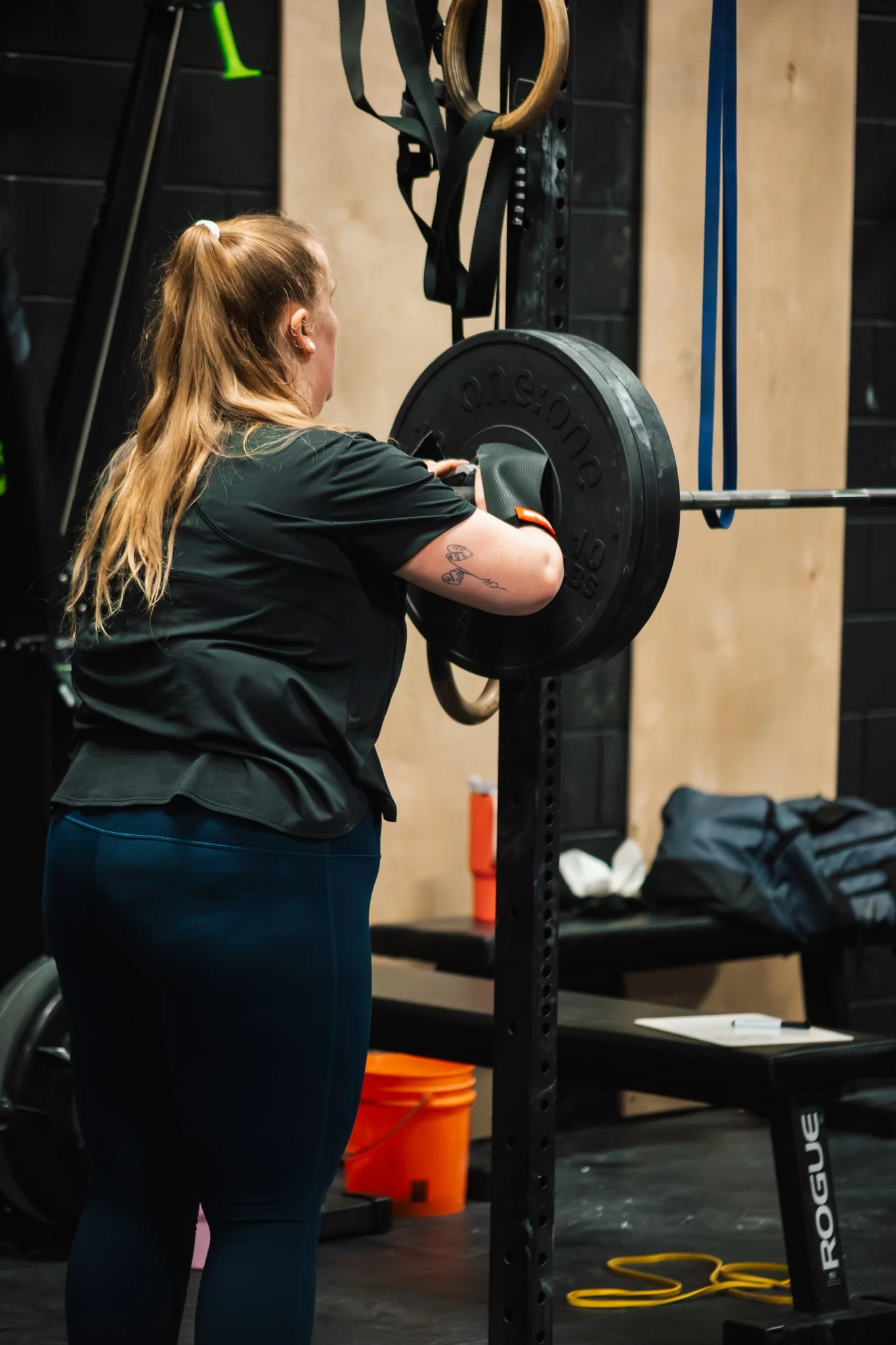 A woman lifting a barbell with weights in a gym.