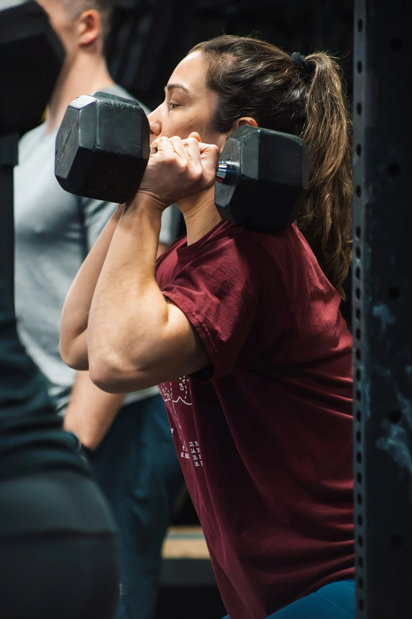 Woman lifting a dumbbell in gym, focused on exercise.