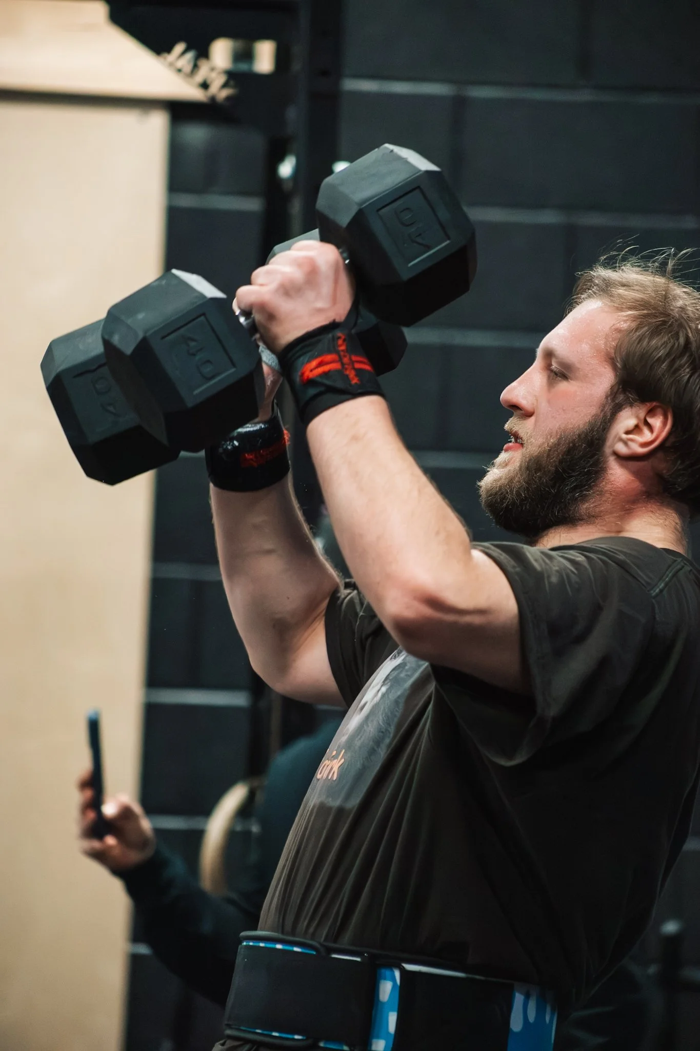 A man lifting a dumbbell during a workout at the gym.