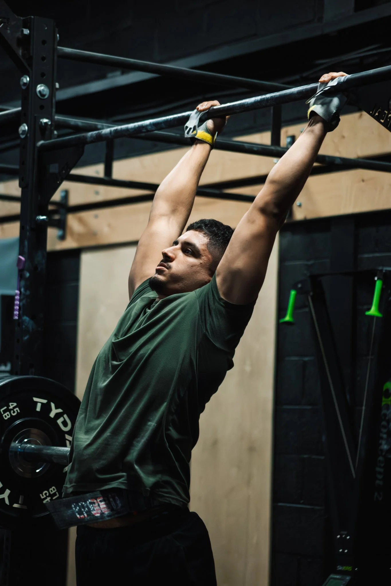 A man lifting a barbell overhead during a workout in a gym.