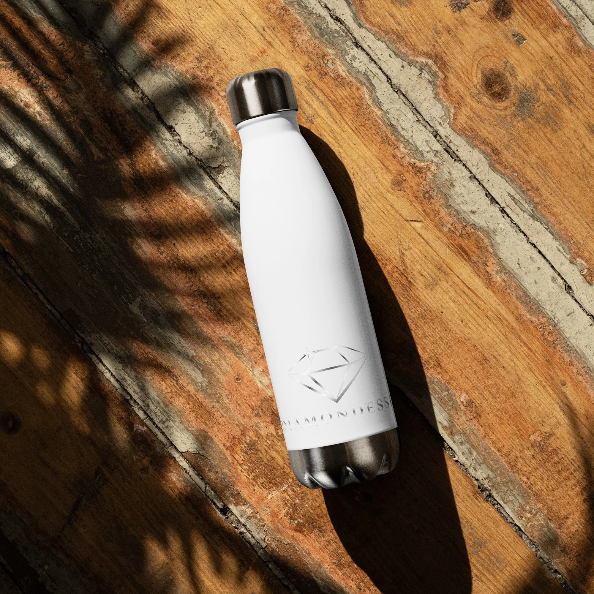 White insulated water bottle with a silver cap and diamond logo on a rustic wooden surface.