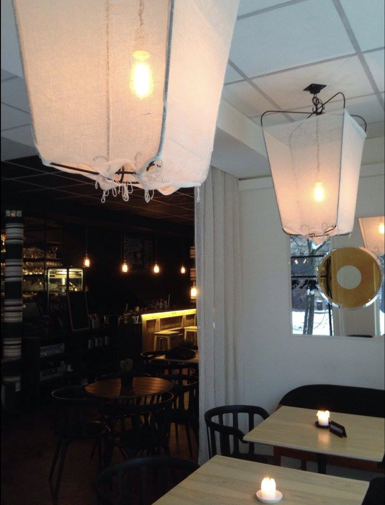 Interior of a cozy restaurant with hanging paper lantern lights, candles on tables, and a dark bar area with pendant lights.
www.gardenlampcollection.com